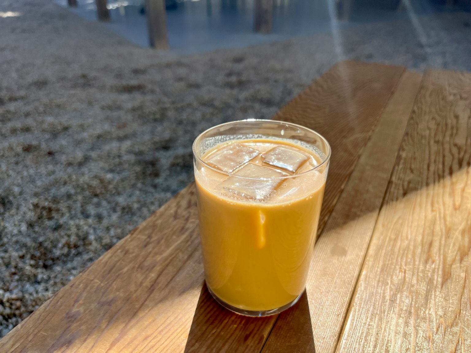 一杯冰咖啡放在木桌上,陽光透過來