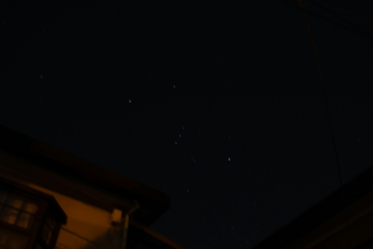 Stars shining in the night sky with rooftops silhouetted