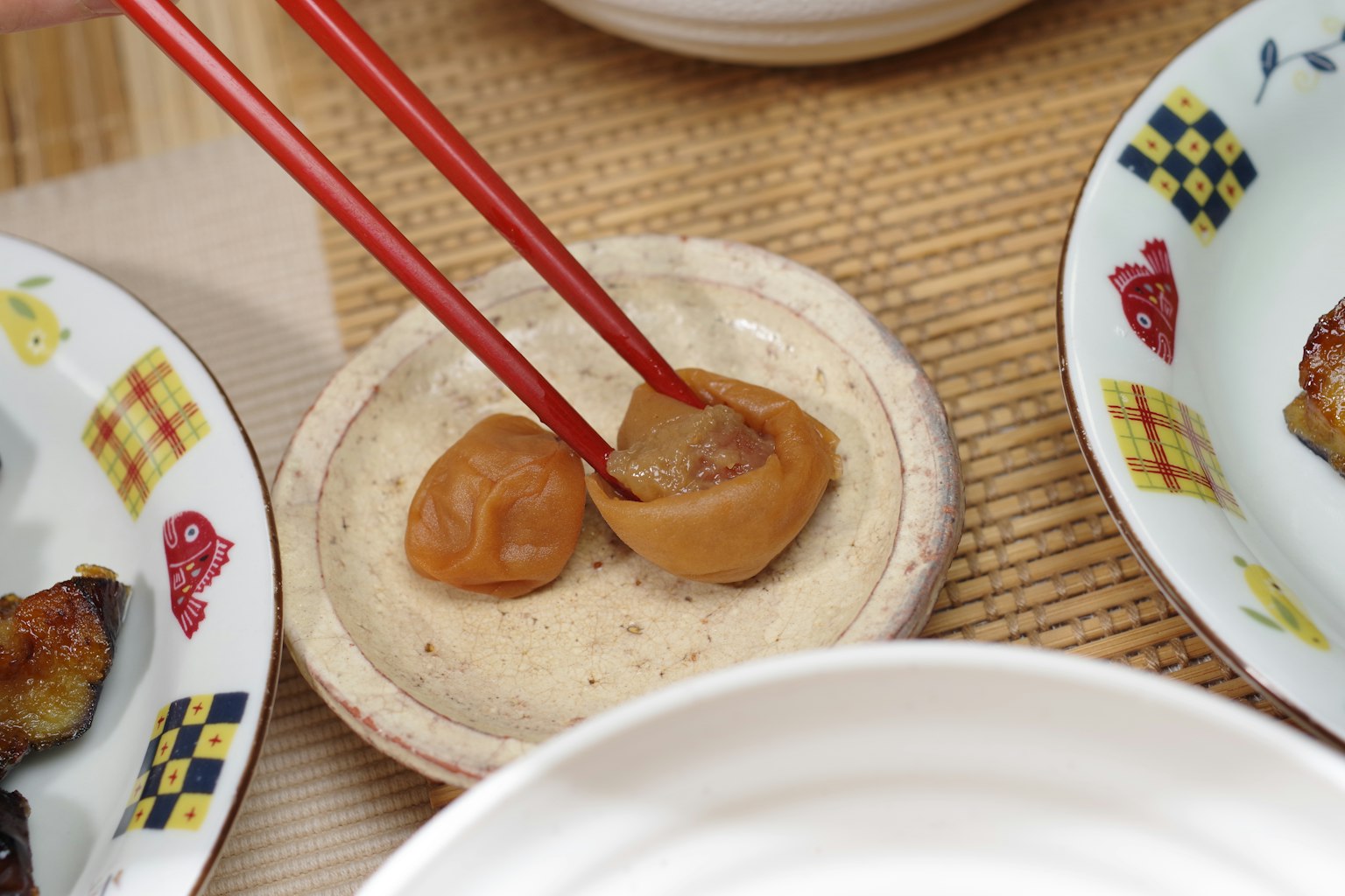 Prunes marinées prises avec des baguettes sur une petite assiette