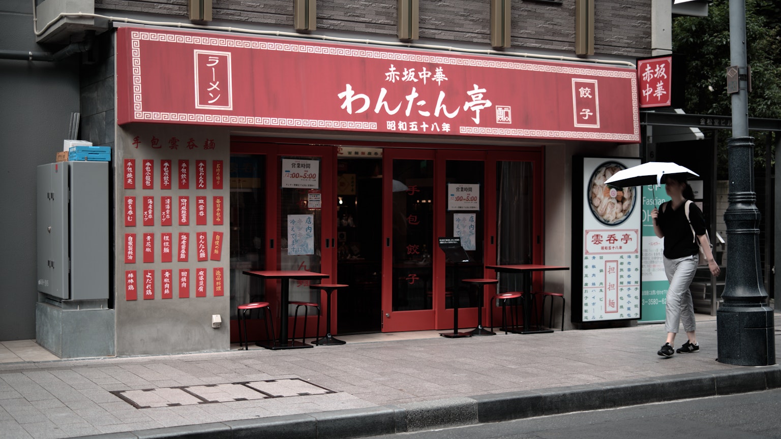 紅色招牌的日本餐廳Wantan Spicy外觀和一位拿著雨傘的女性