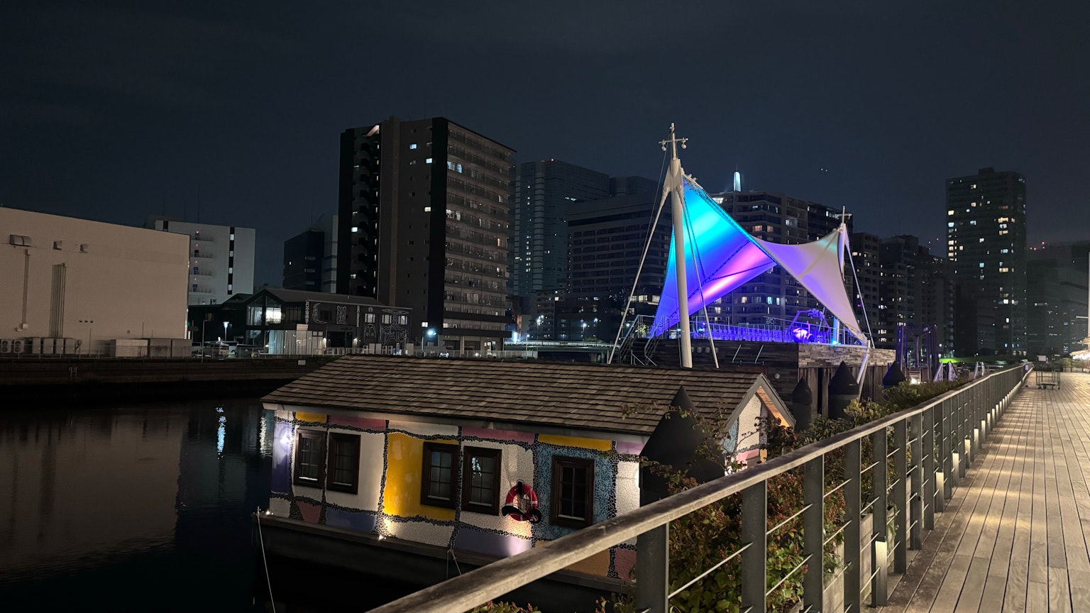 บ้านลอยน้ำที่มีเต็นท์สีสันสดใสอยู่ข้างแม่น้ำในตอนกลางคืน