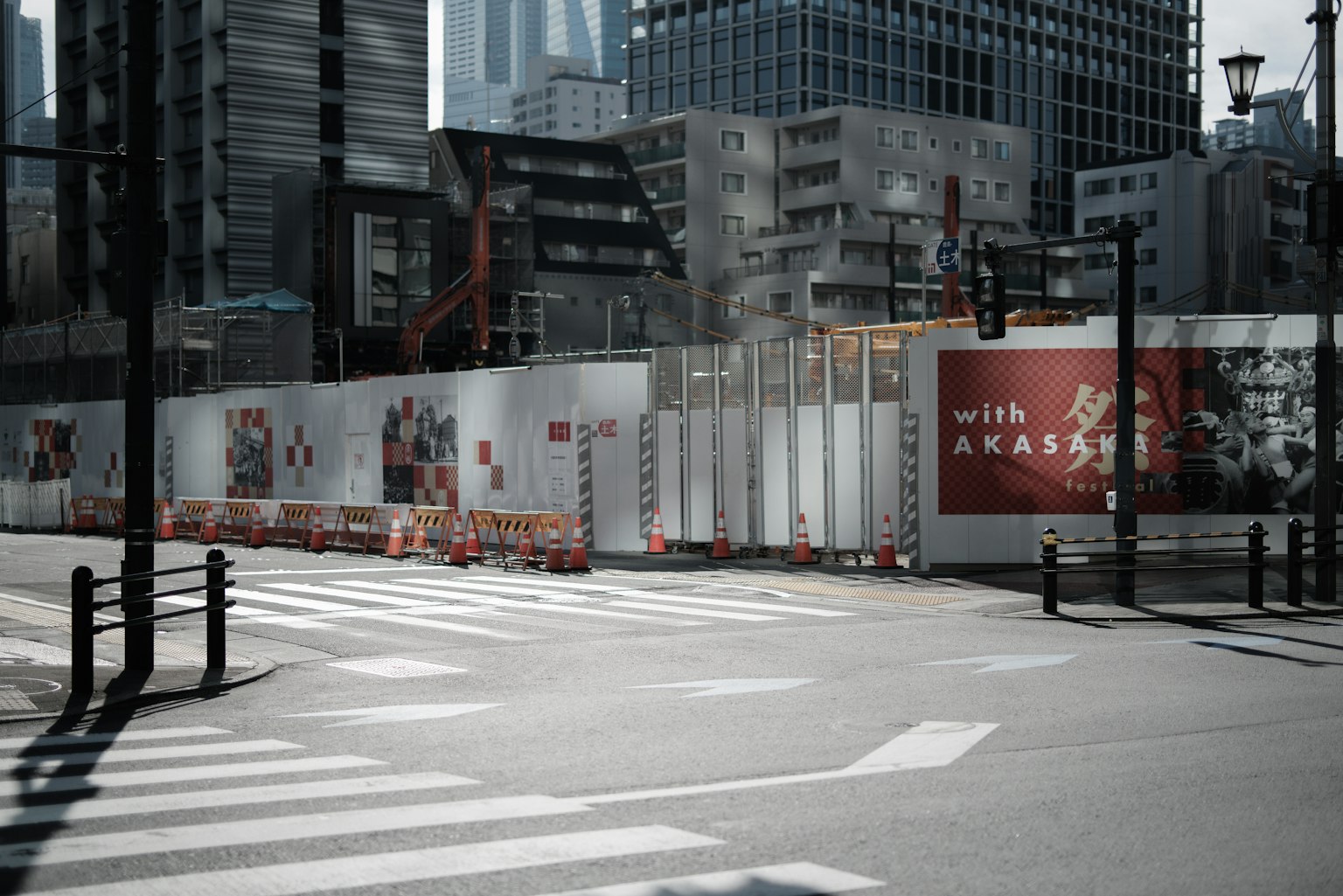 城市工地在斑馬線旁邊，特點是高樓和白色圍欄