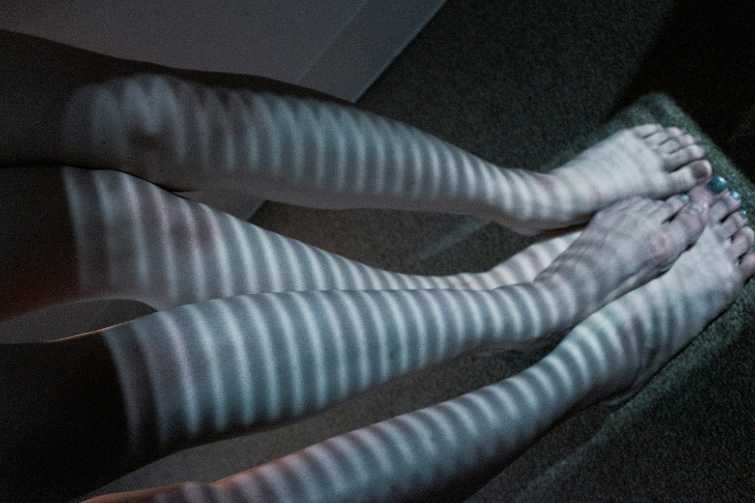 Piedi che indossano calze a righe bianche che proiettano ombre a motivi