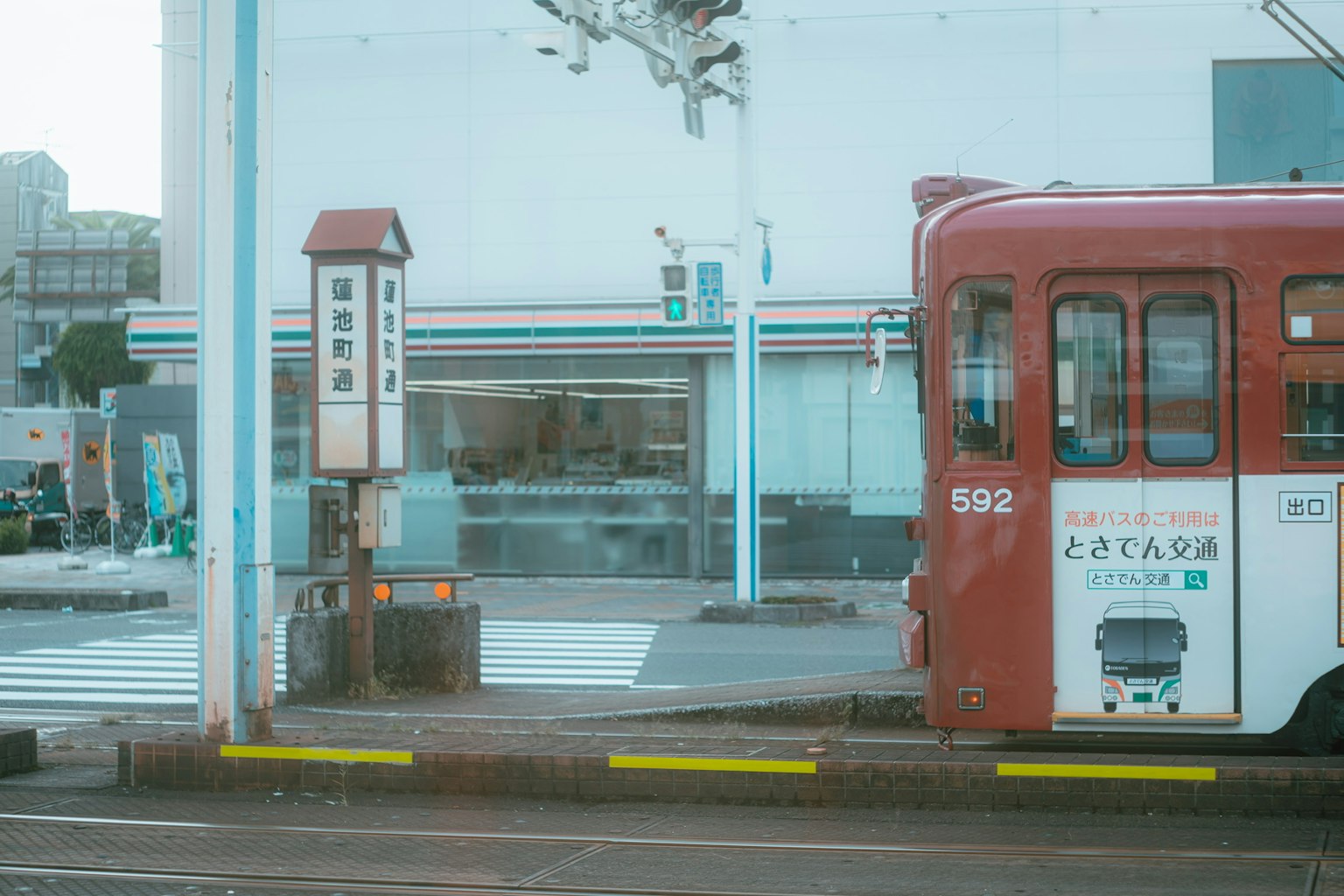 รถรางสีแดงที่ทางม้าลายพร้อมกับ 7-Eleven ในพื้นหลัง