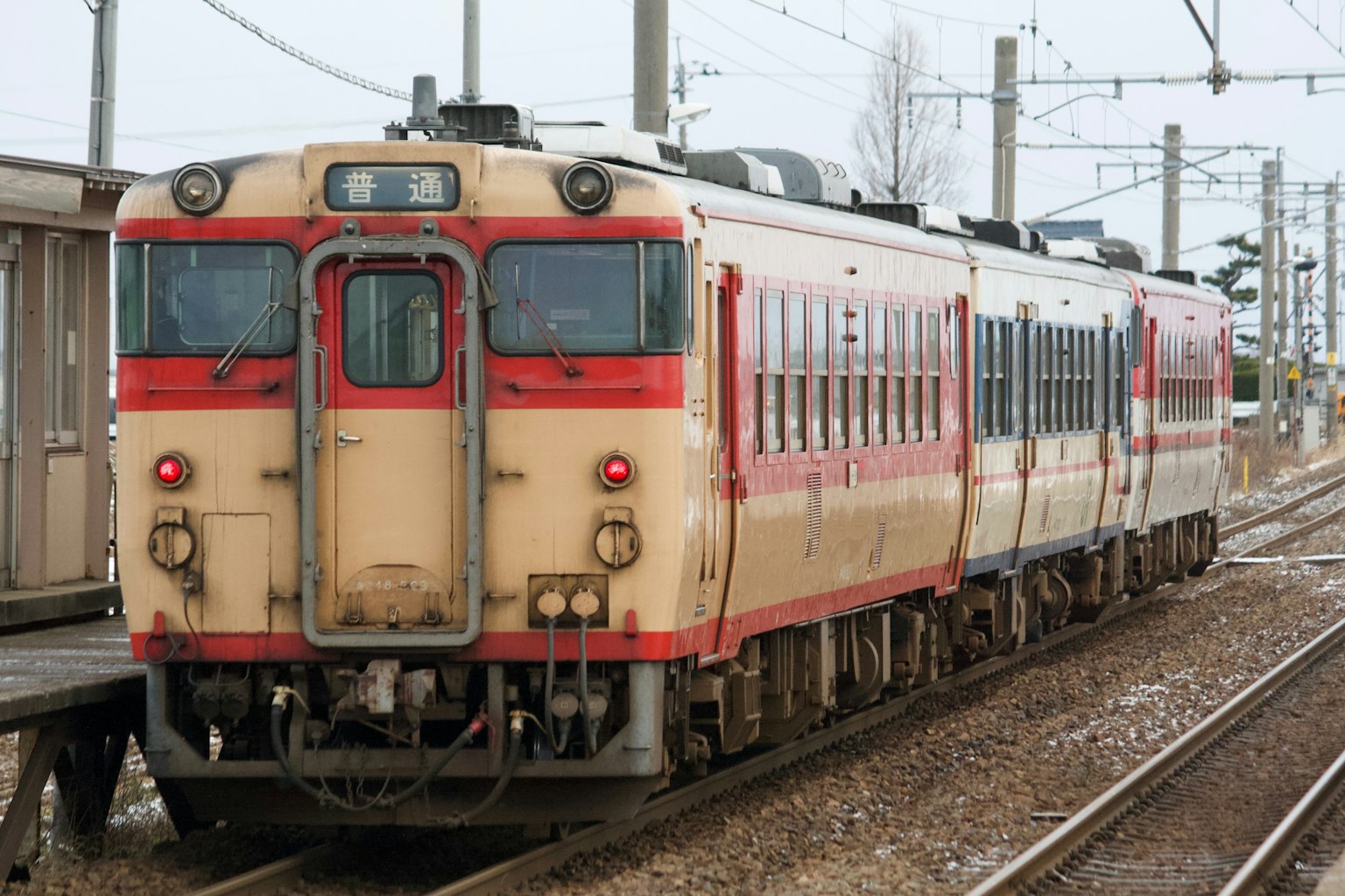 Sebuah kereta merah dan krim berhenti di stasiun