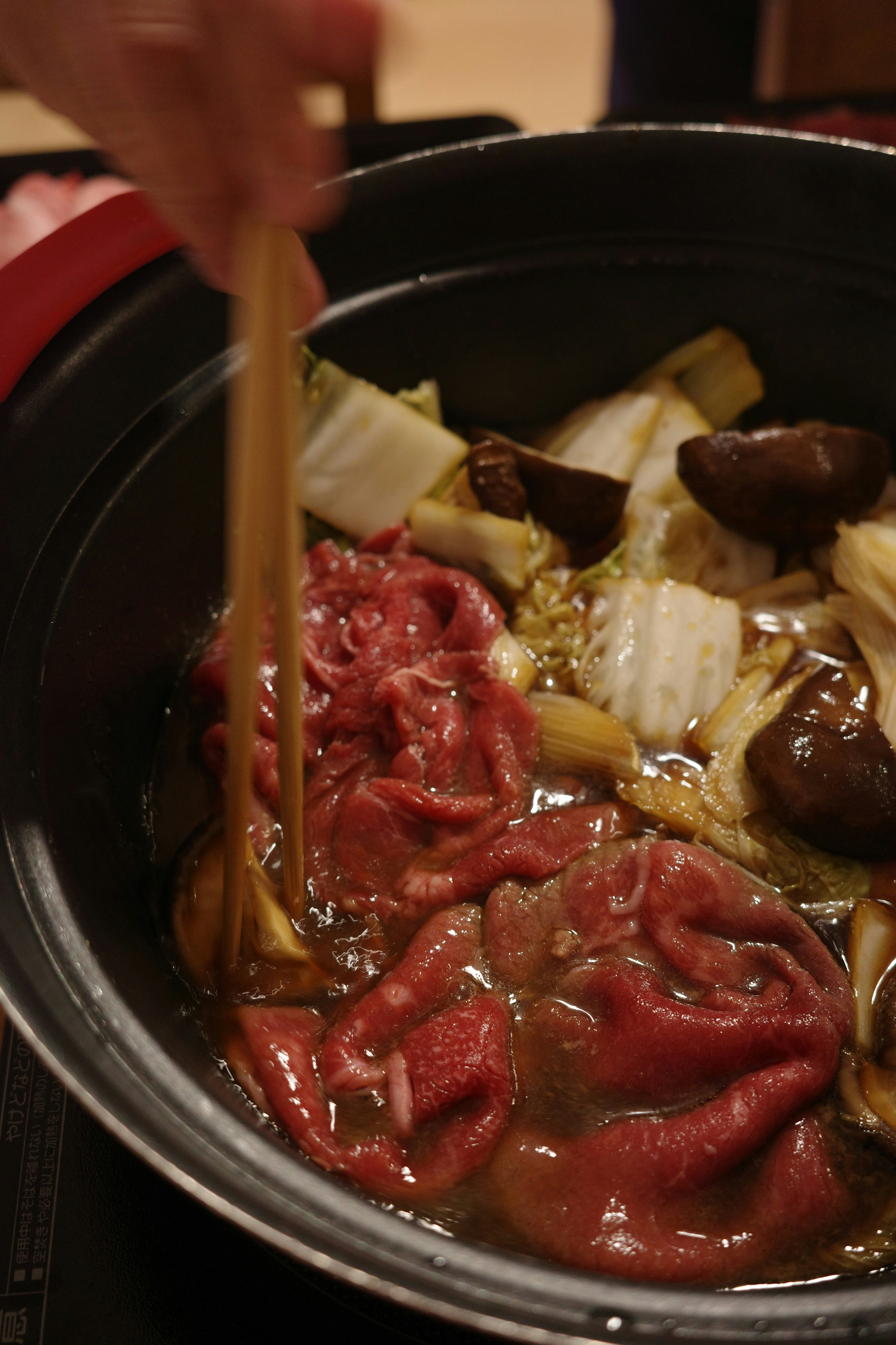 鍋で煮込む赤いソースの肉と野菜