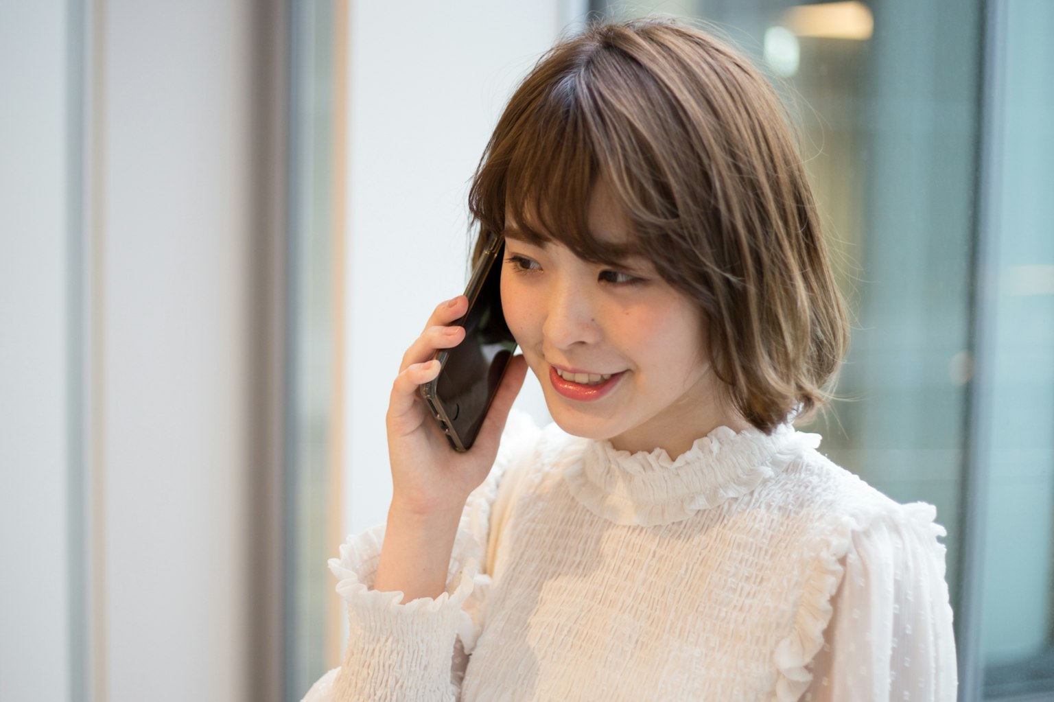 Hình ảnh của một người phụ nữ đang nói chuyện qua điện thoại mặc áo blouse trắng