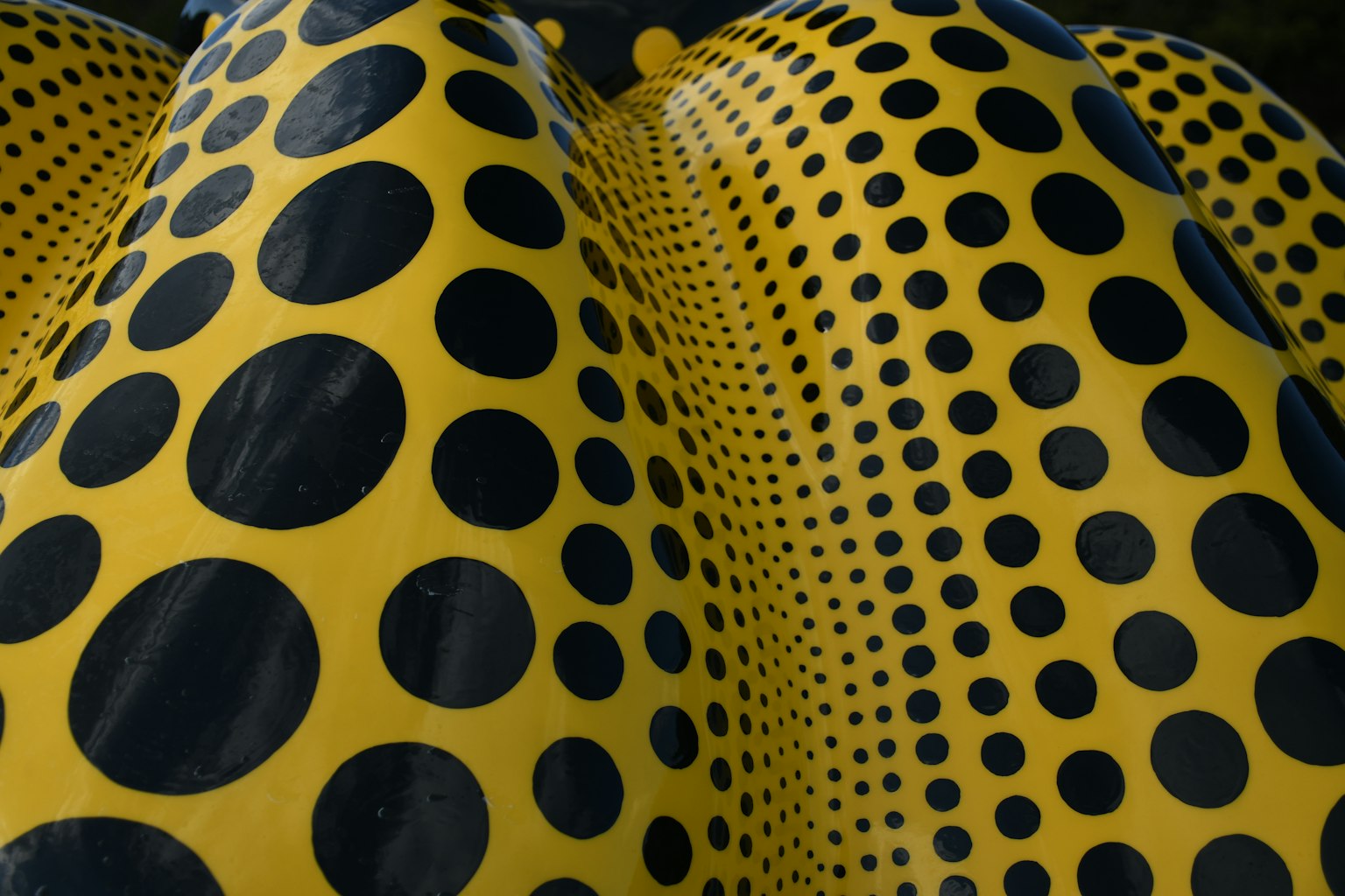 Nahaufnahme eines markanten Kunstwerks mit gelbem Hintergrund und schwarzen Punkten