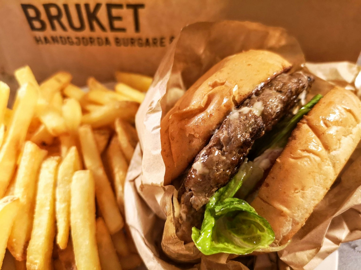 Delicious burger with lettuce and fries in a branded box from Bruket