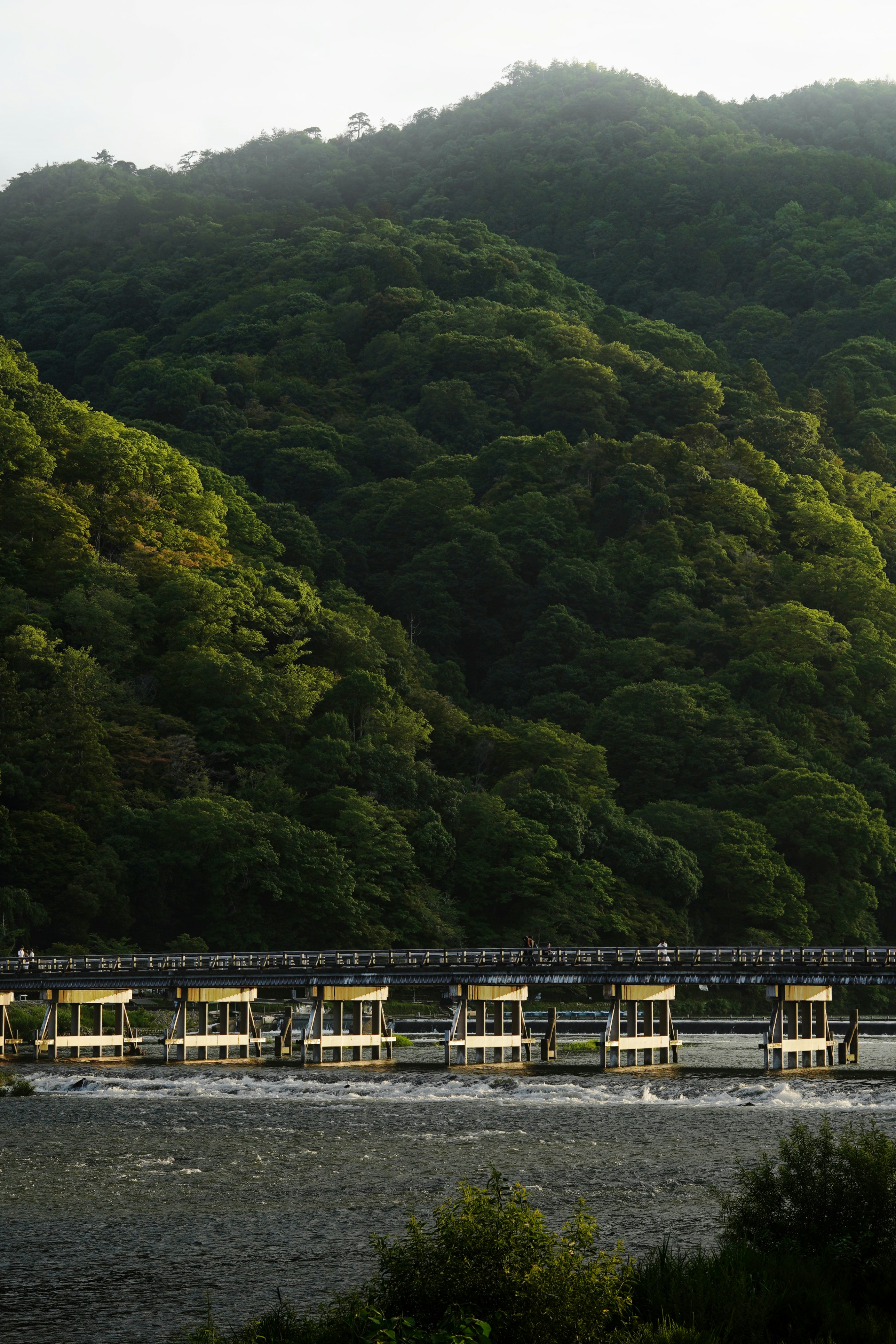 夕暮れの渡月橋と川沿いの山並み