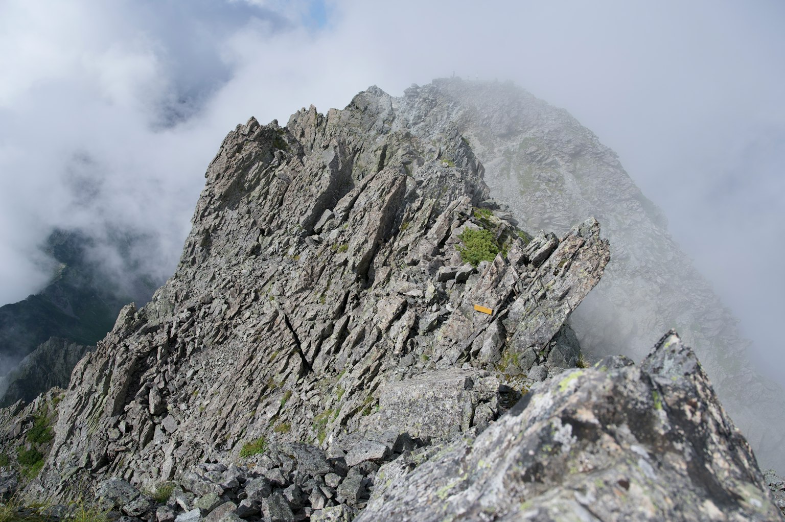 Zackiger Felsgipfel umhüllt von Nebel und Wolken