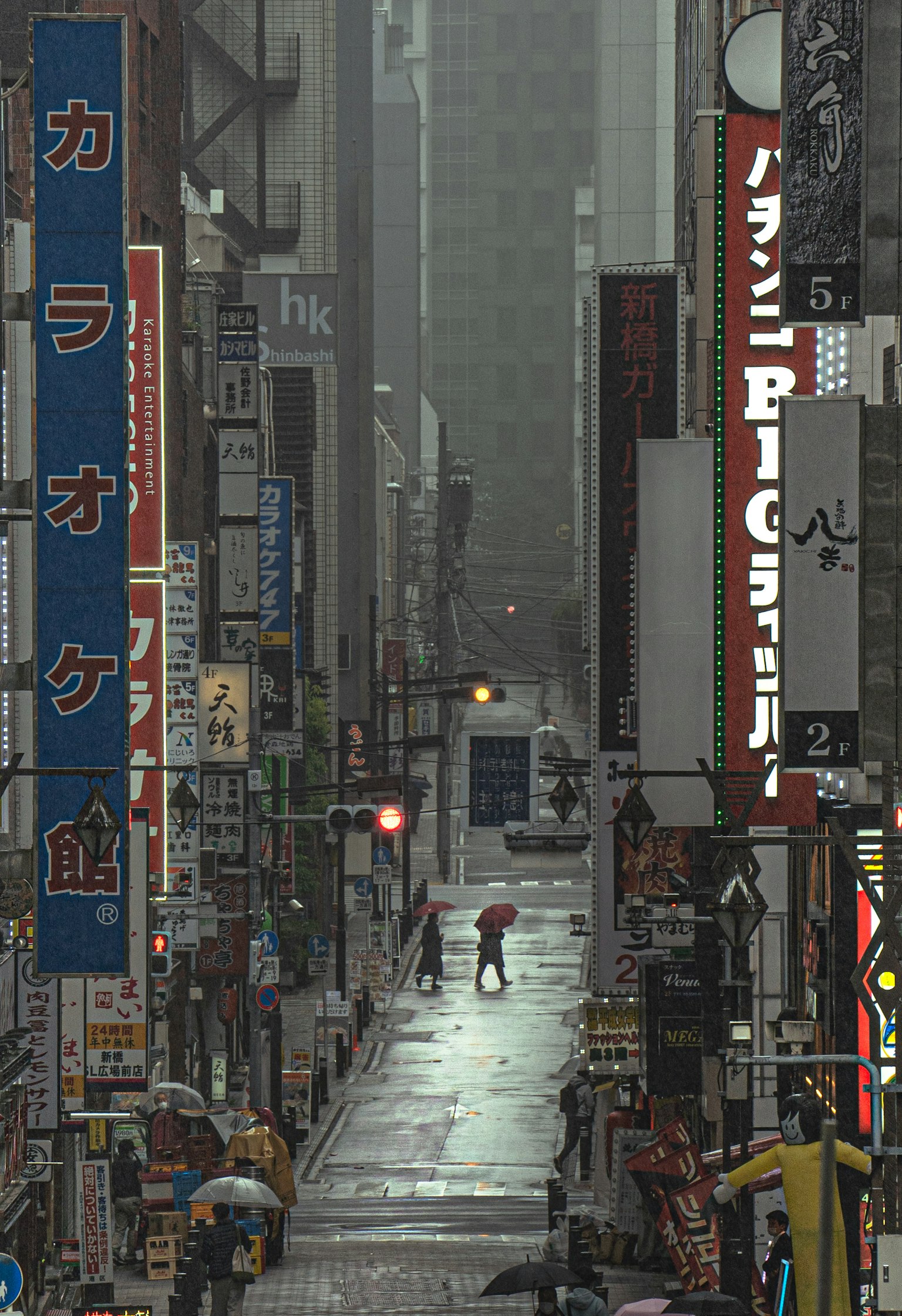 雨の中の都市の通りに立つ人々とネオン看板