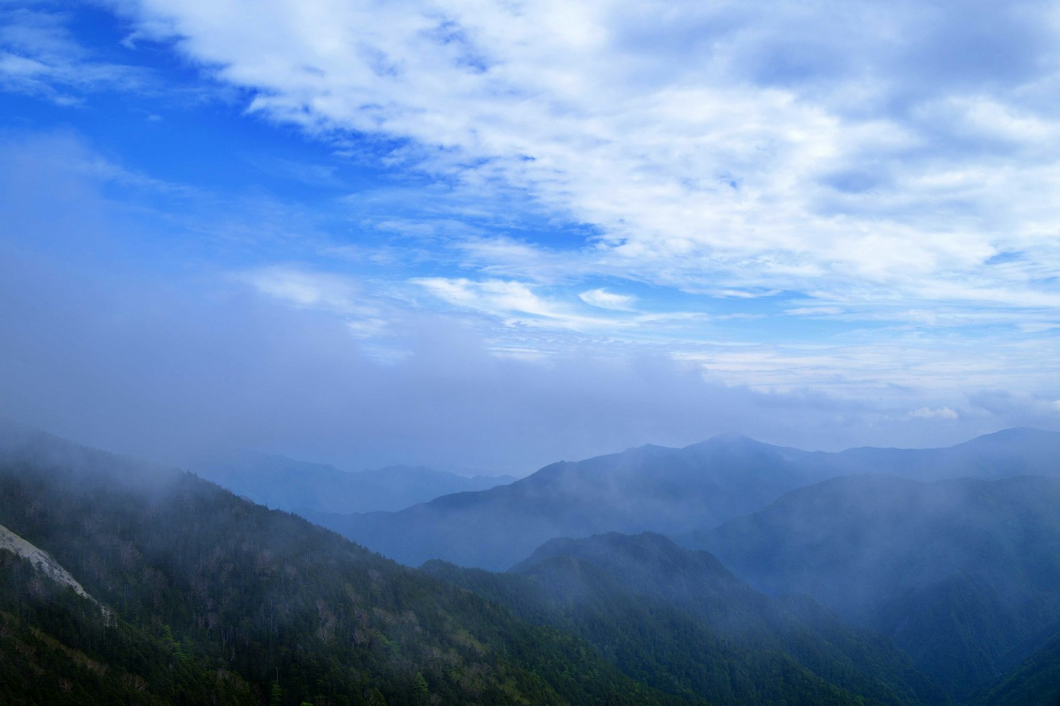 蓝天下被雾气笼罩的山脉风景