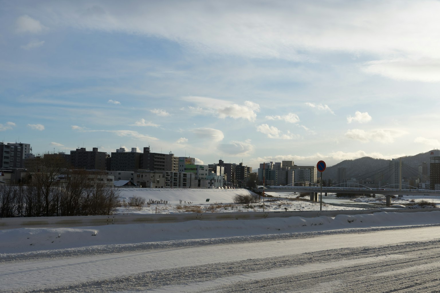 Snow-covered landscape with urban skyline under blue sky