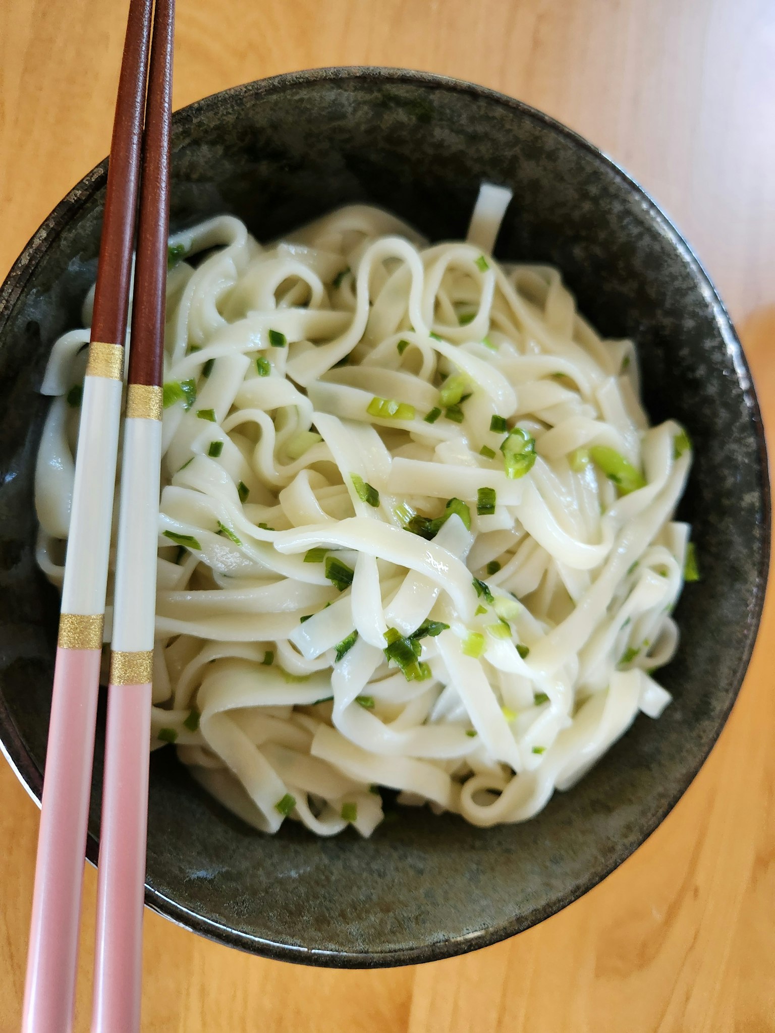 一碗白色米粉，上面撒有绿色香草
