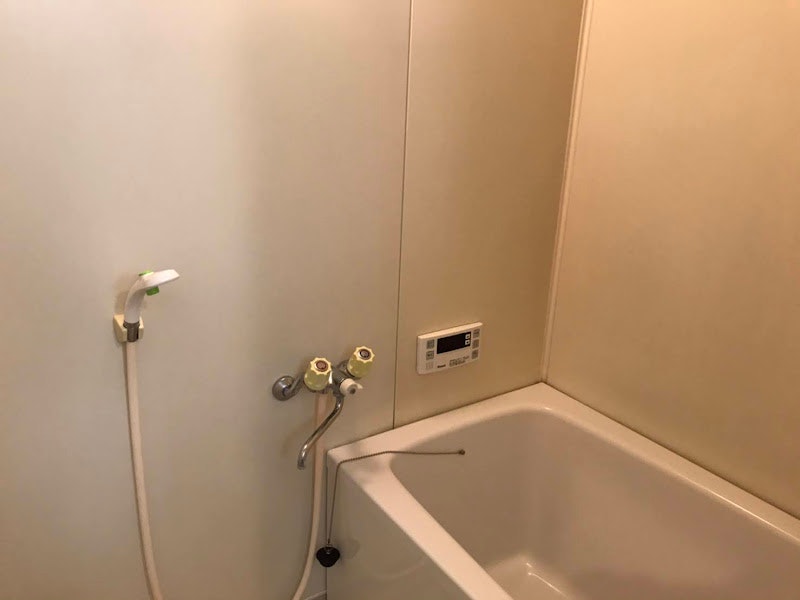 pared de baño limpia con bañera y grifo de ducha