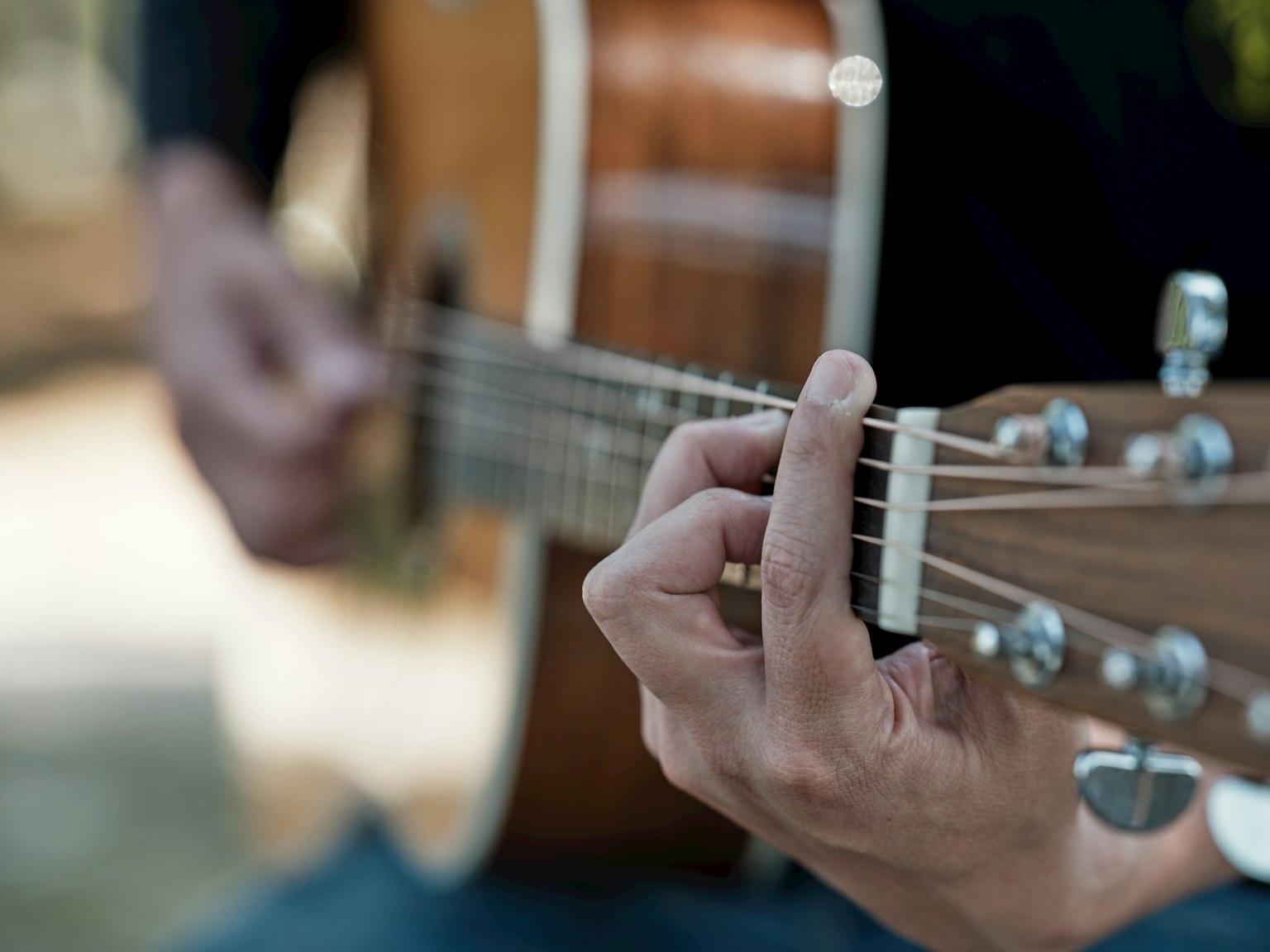 Primer plano de manos tocando una guitarra acústica