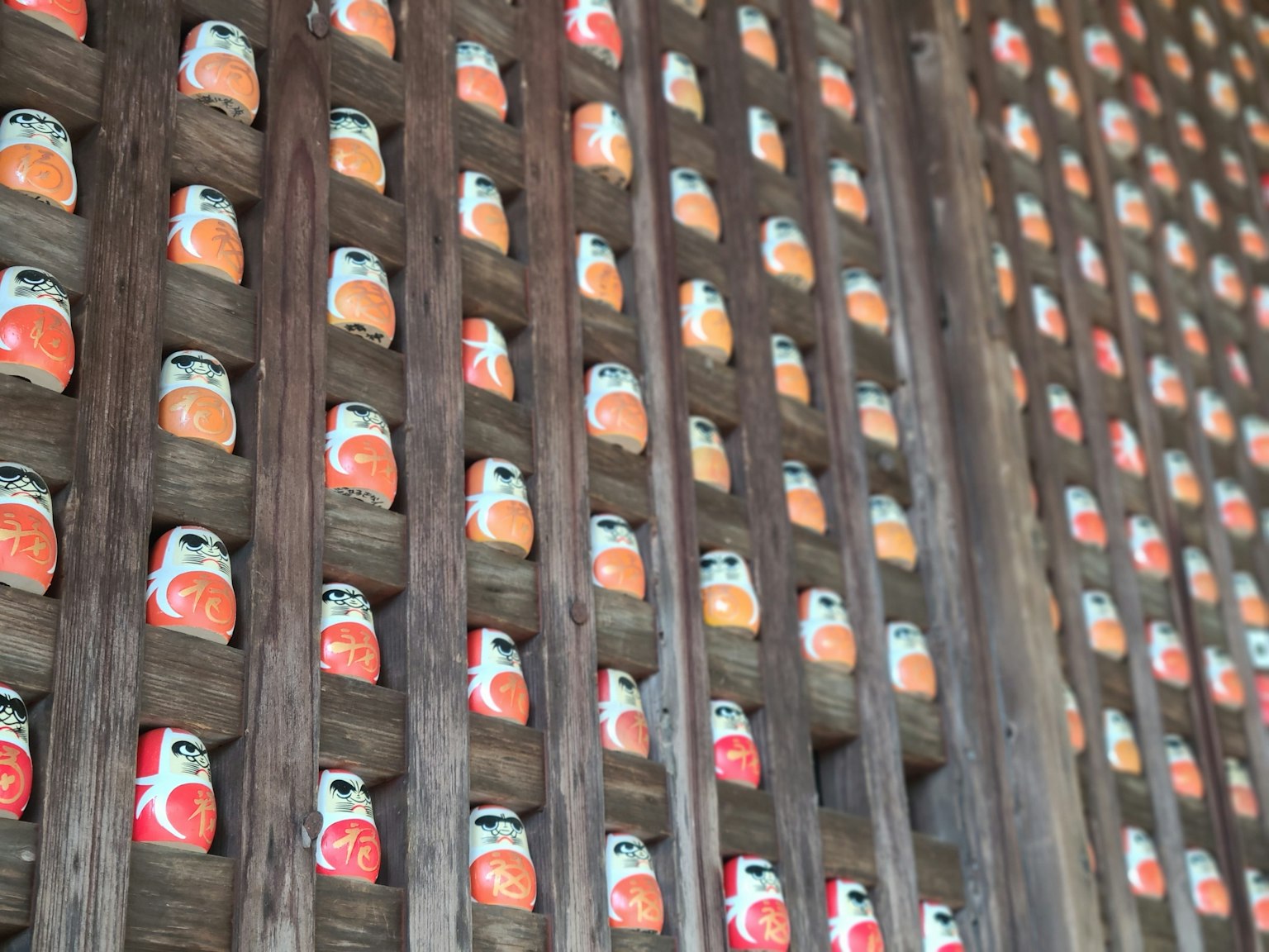 Un mur en bois affichant de nombreux poupées Daruma