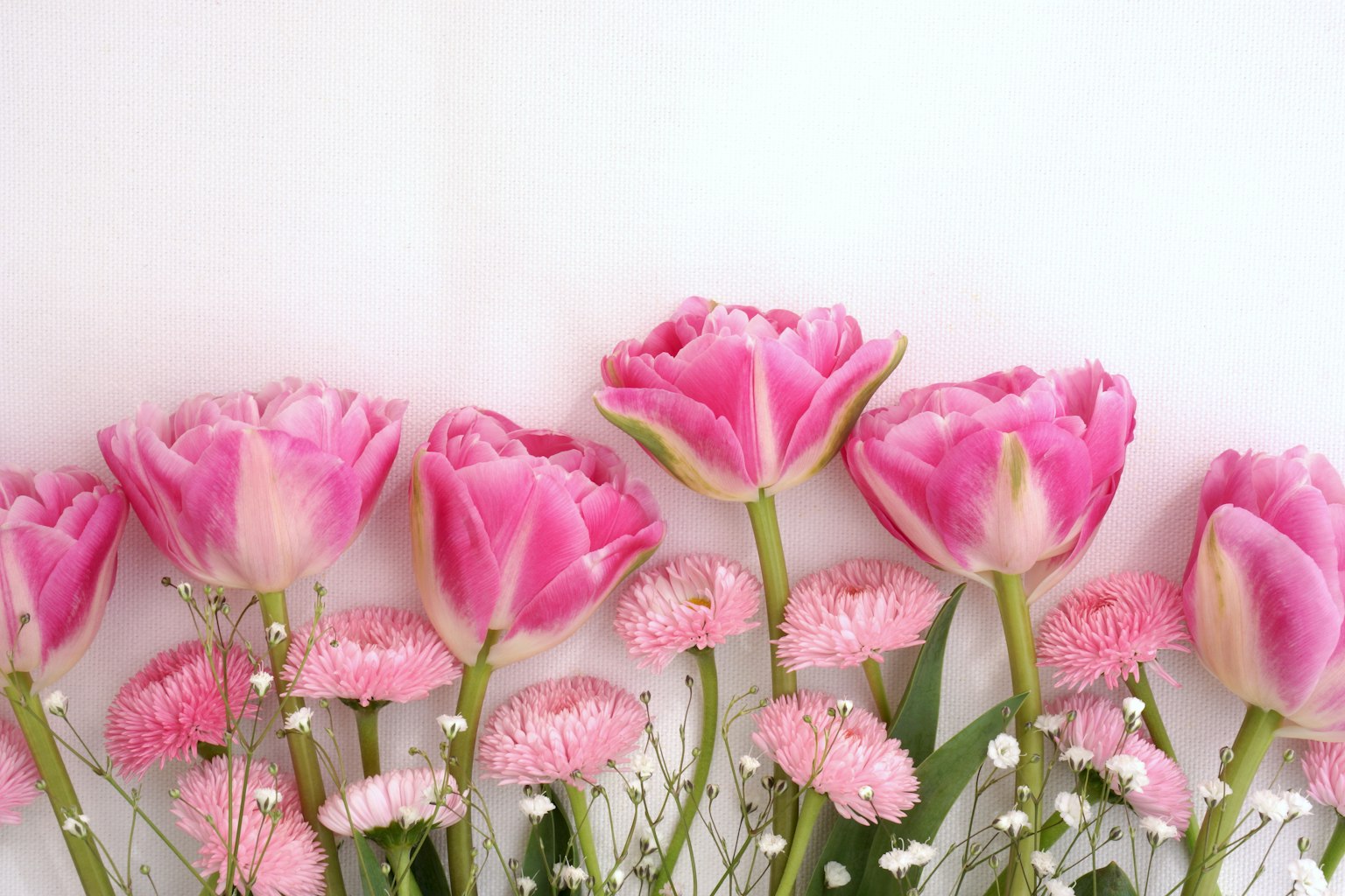 Un bouquet avec des tulipes roses et de petites fleurs disposées ensemble