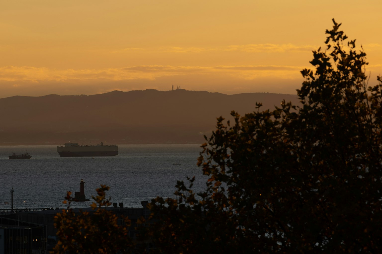 Vista del atardecer sobre el mar con montañas al fondo y un barco en el agua