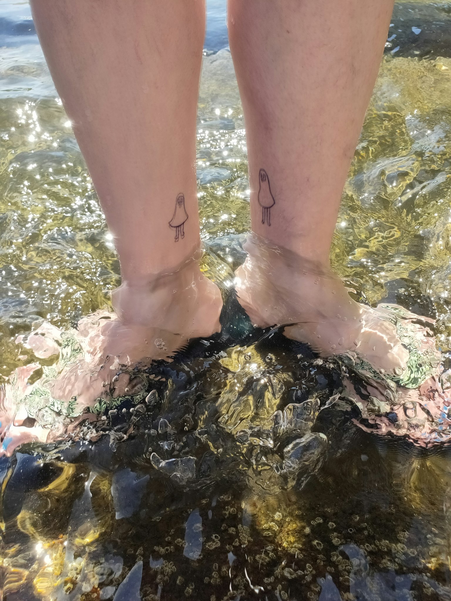 Füße im Wasser mit sichtbaren Tattoos