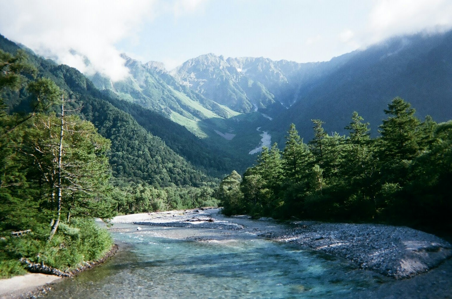 Malersicher Blick auf ein Tal, umgeben von Bergen mit einem klaren Bach