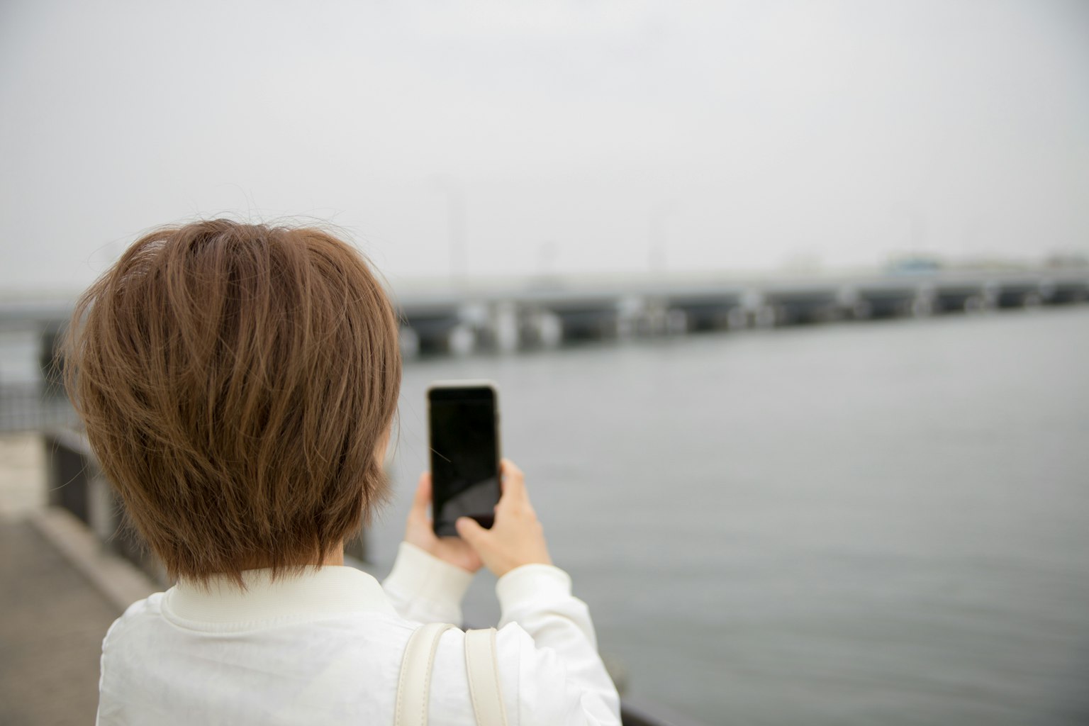 一位女性手持智慧型手機面朝大海
