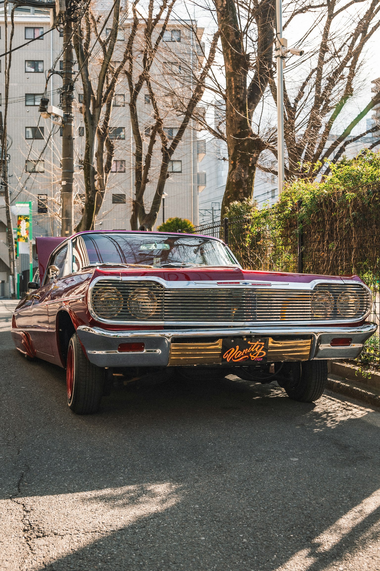 A red classic car parked on the street with surrounding buildings