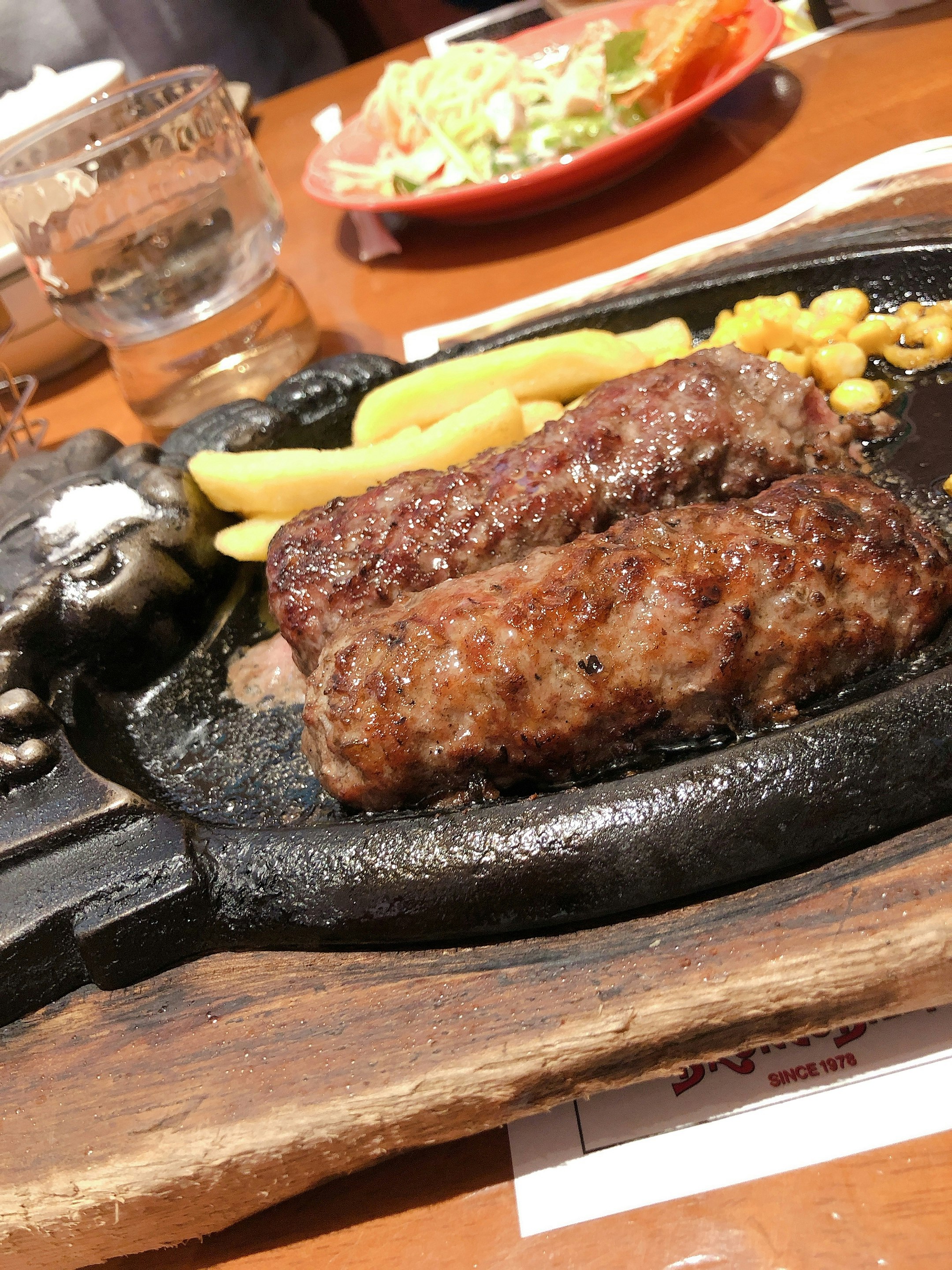 hamburger steak di atas hot plate yang sedang mendesis dengan lauk