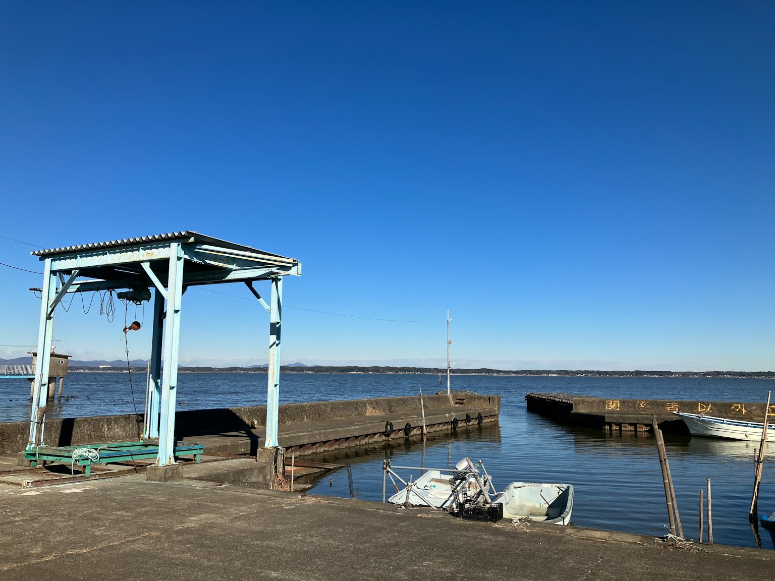 Vista panoramica di un porto sotto un cielo blu con un capanno e piccole barche