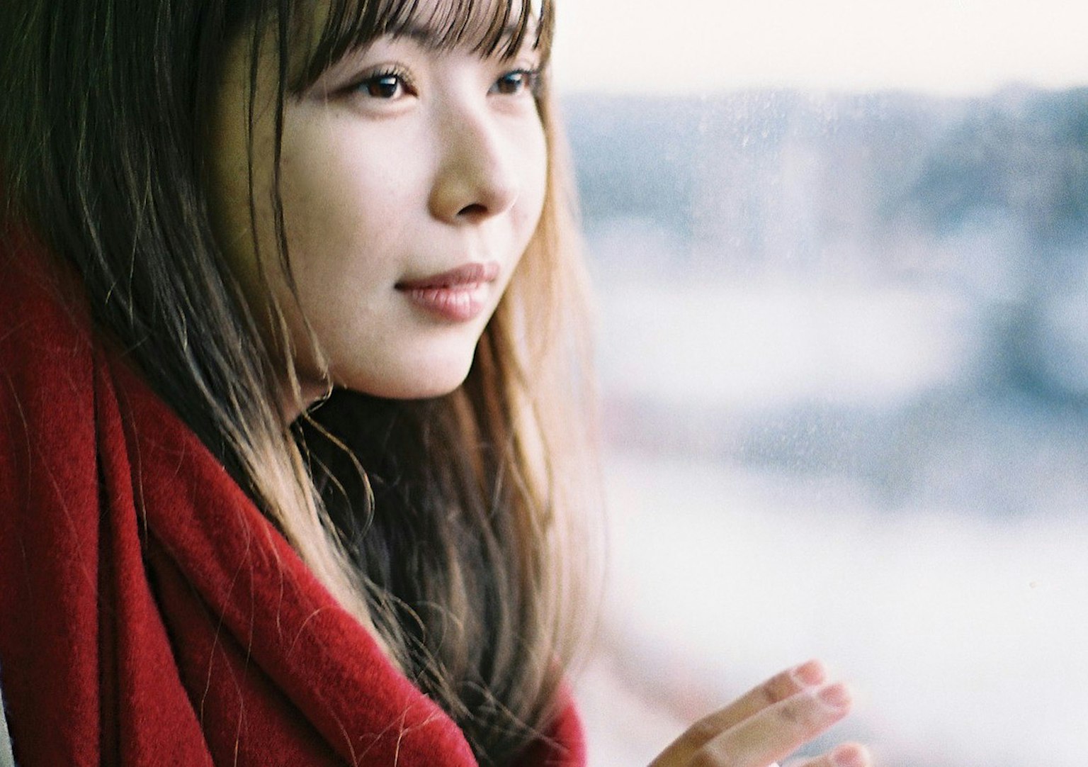 身披红色围巾的女性凝视窗外的肖像