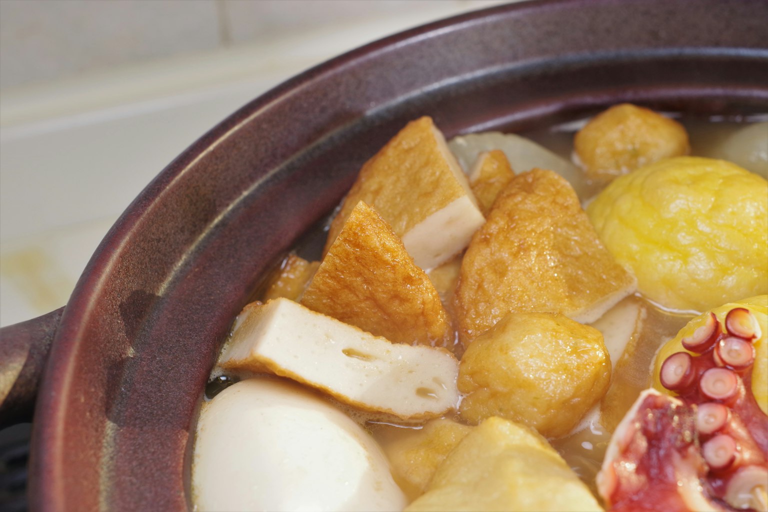 Ein Topf gefüllt mit frittiertem Tofu, Fischkuchen, Oktopus und Gemüse