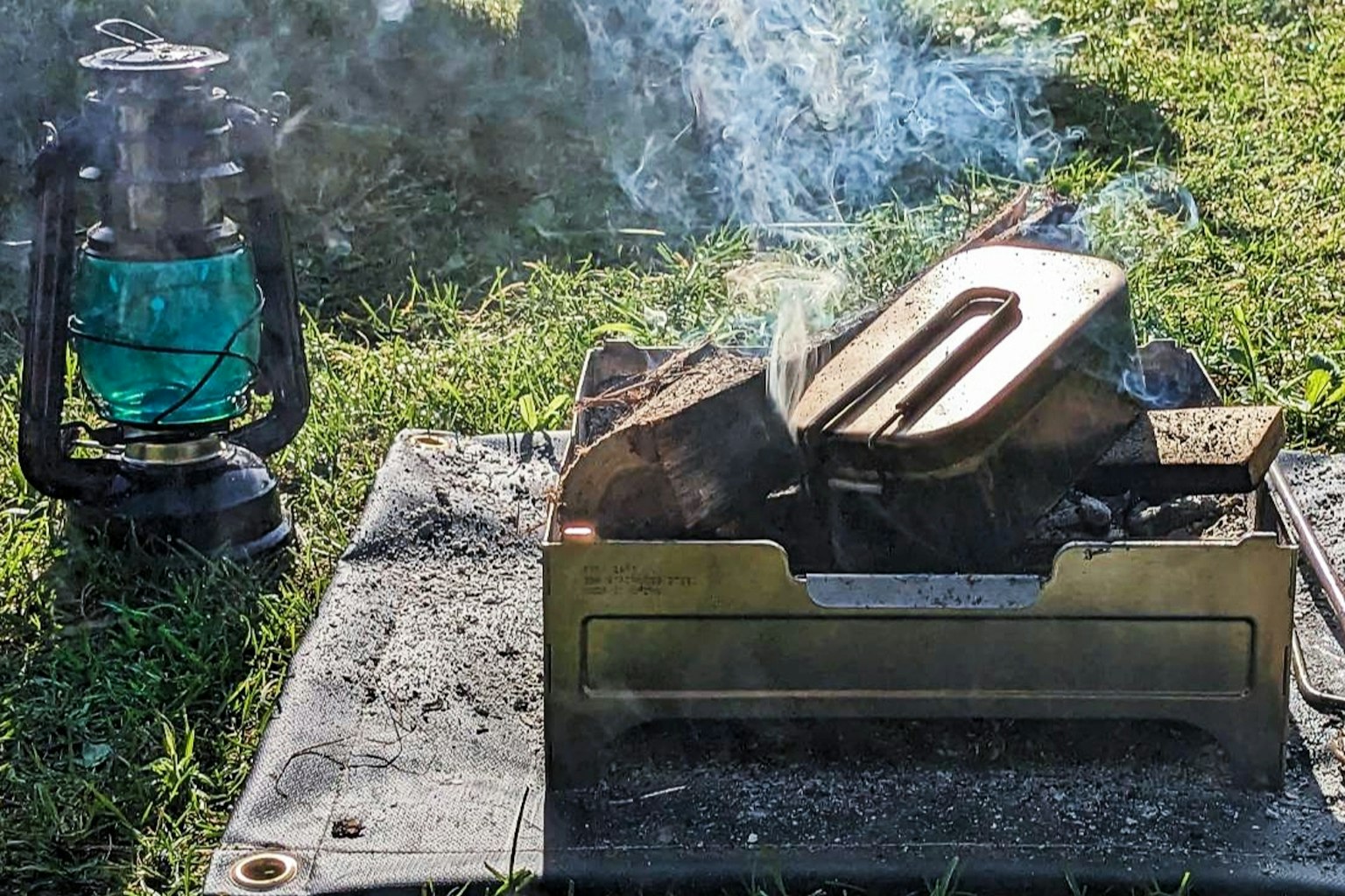 Lanterna verde accanto a un fornello da campeggio fumante con legna