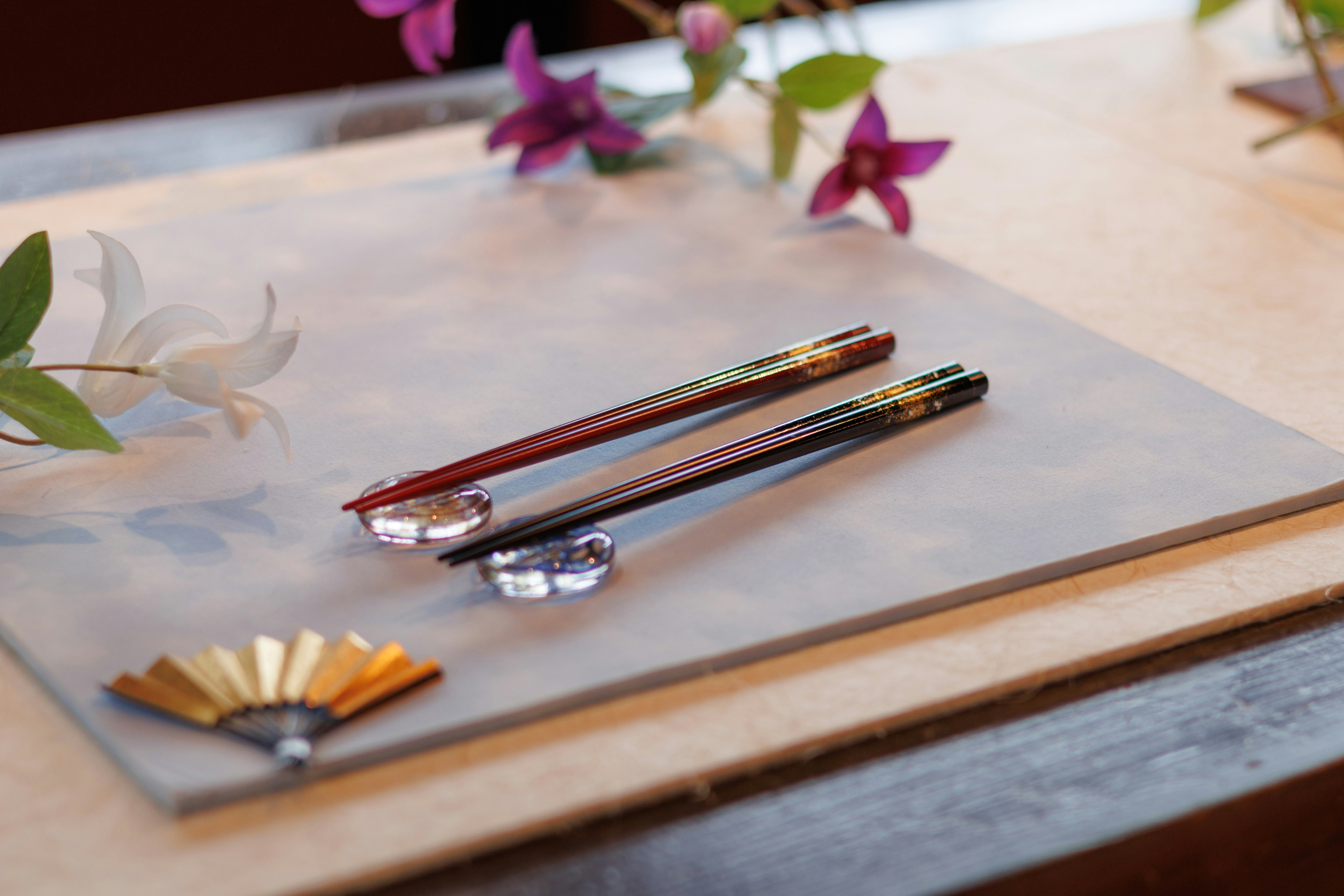 花びらと小さな扇子が添えられた筆記具のあるテーブル