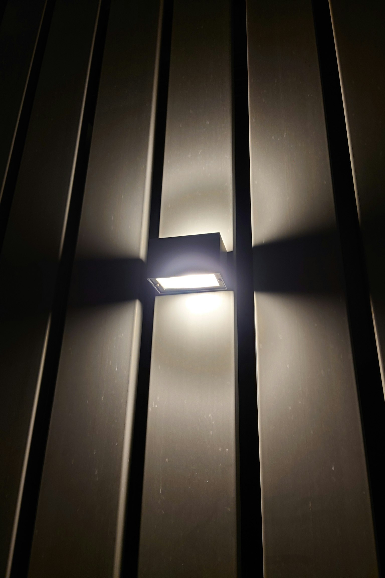 A simple wall light emitting light against a dark background