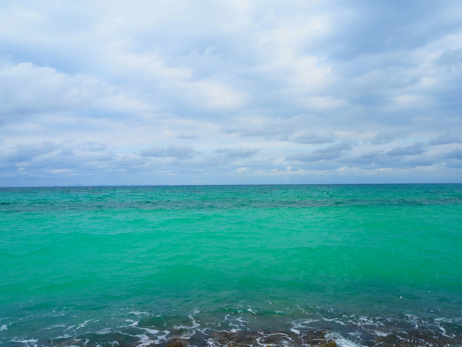 Vue de plage sereine avec eau turquoise et ciel nuageux