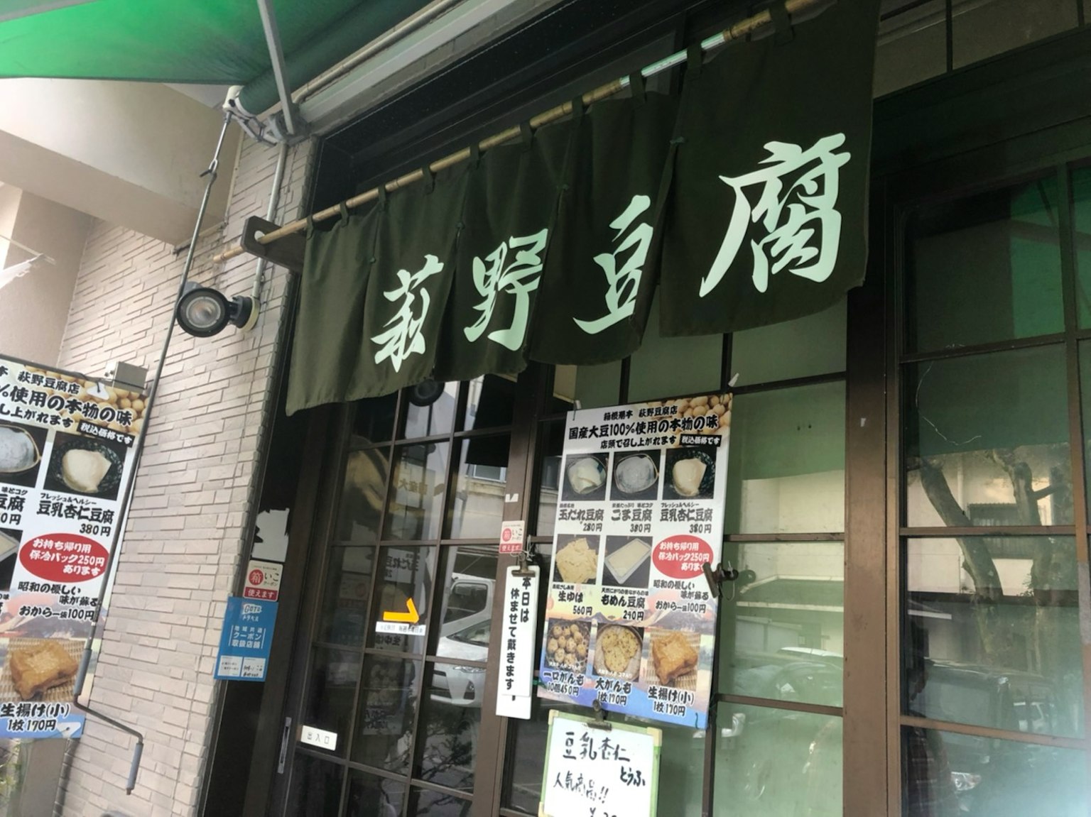 ภายนอกของร้านอาหารญี่ปุ่นที่มีป้ายสีเขียวและตัวอักษรคันจิ