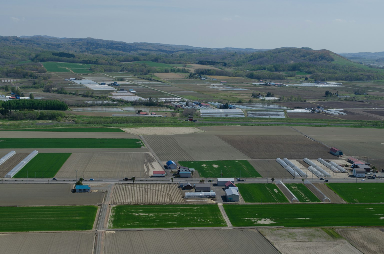 Vue aérienne de terres agricoles vertes avec des serres et des bâtiments ruraux