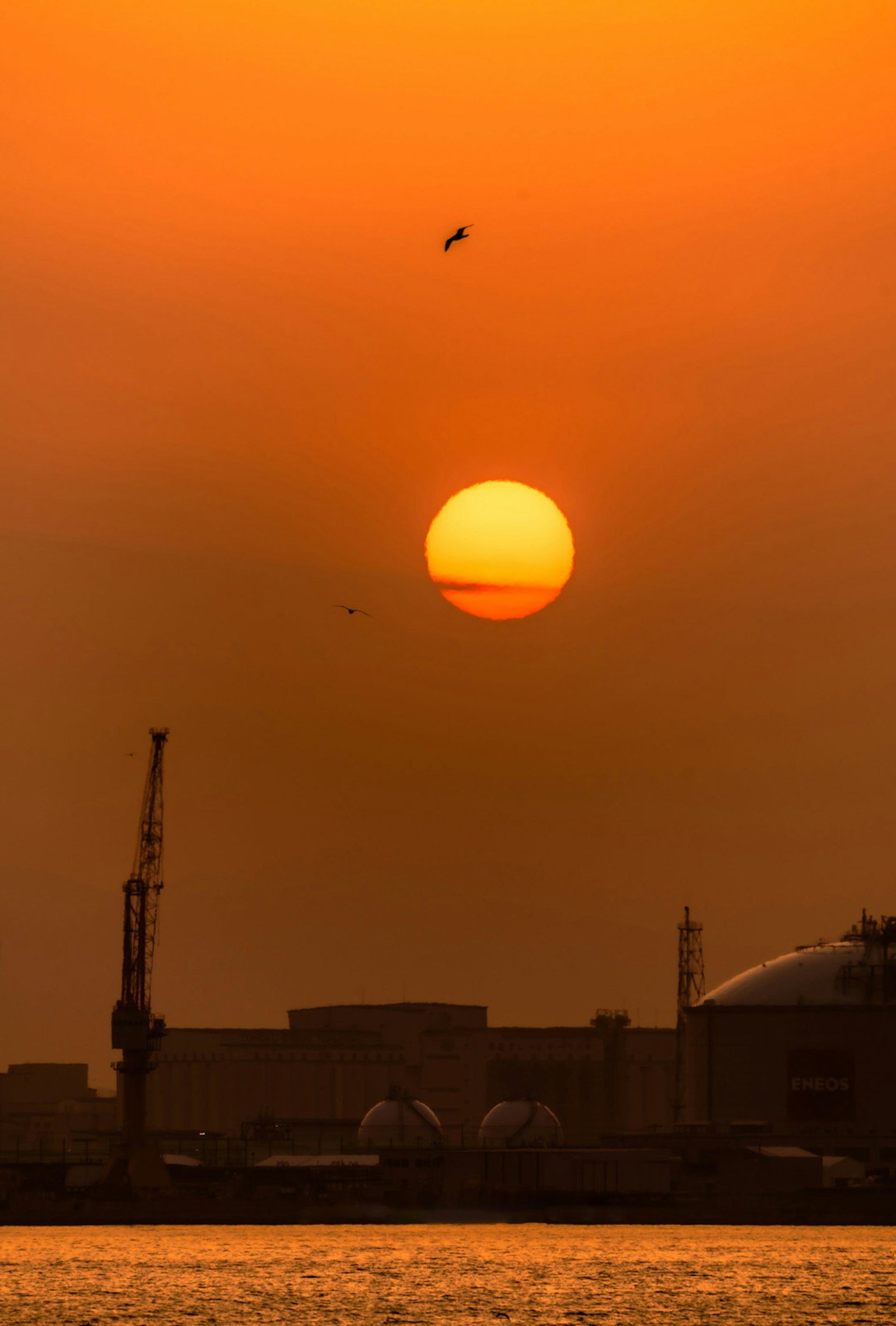 Sunset over the sea with industrial silhouettes