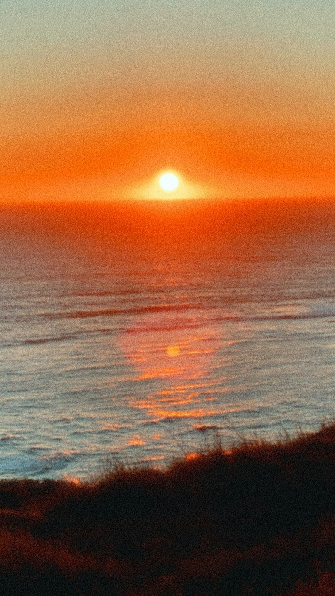 夕焼けの海と水平線に沈む太陽の光