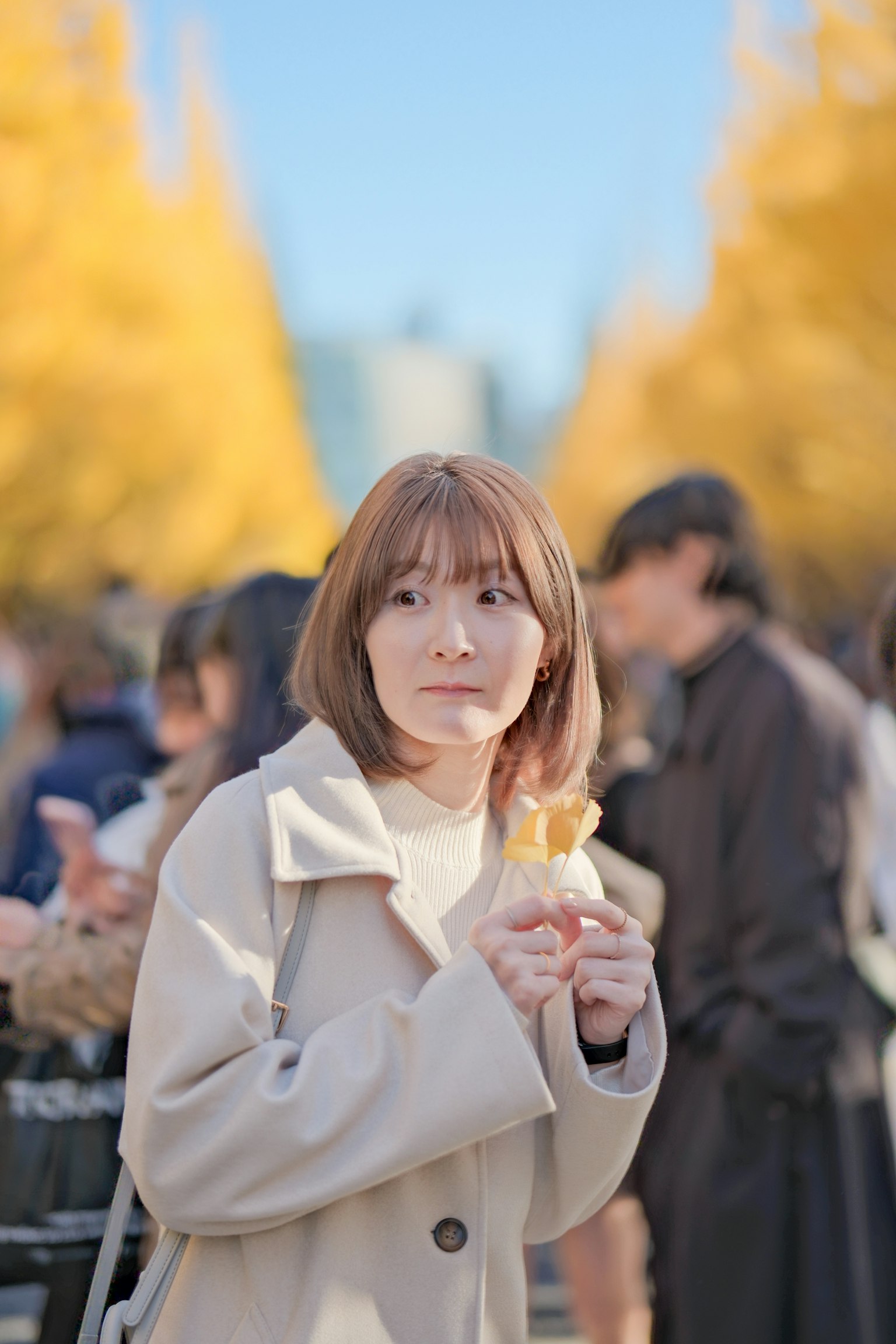 Wanita memegang es krim di antara pohon ginkgo kuning