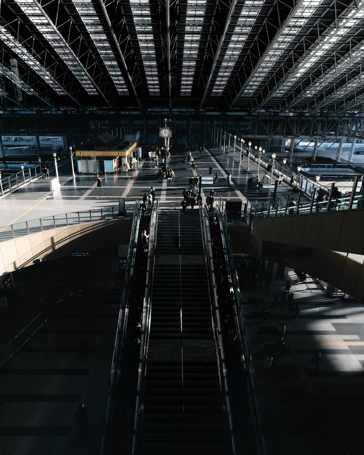 Vista interior de una amplia estación de tren con un gran techo, escaleras y plataformas visibles