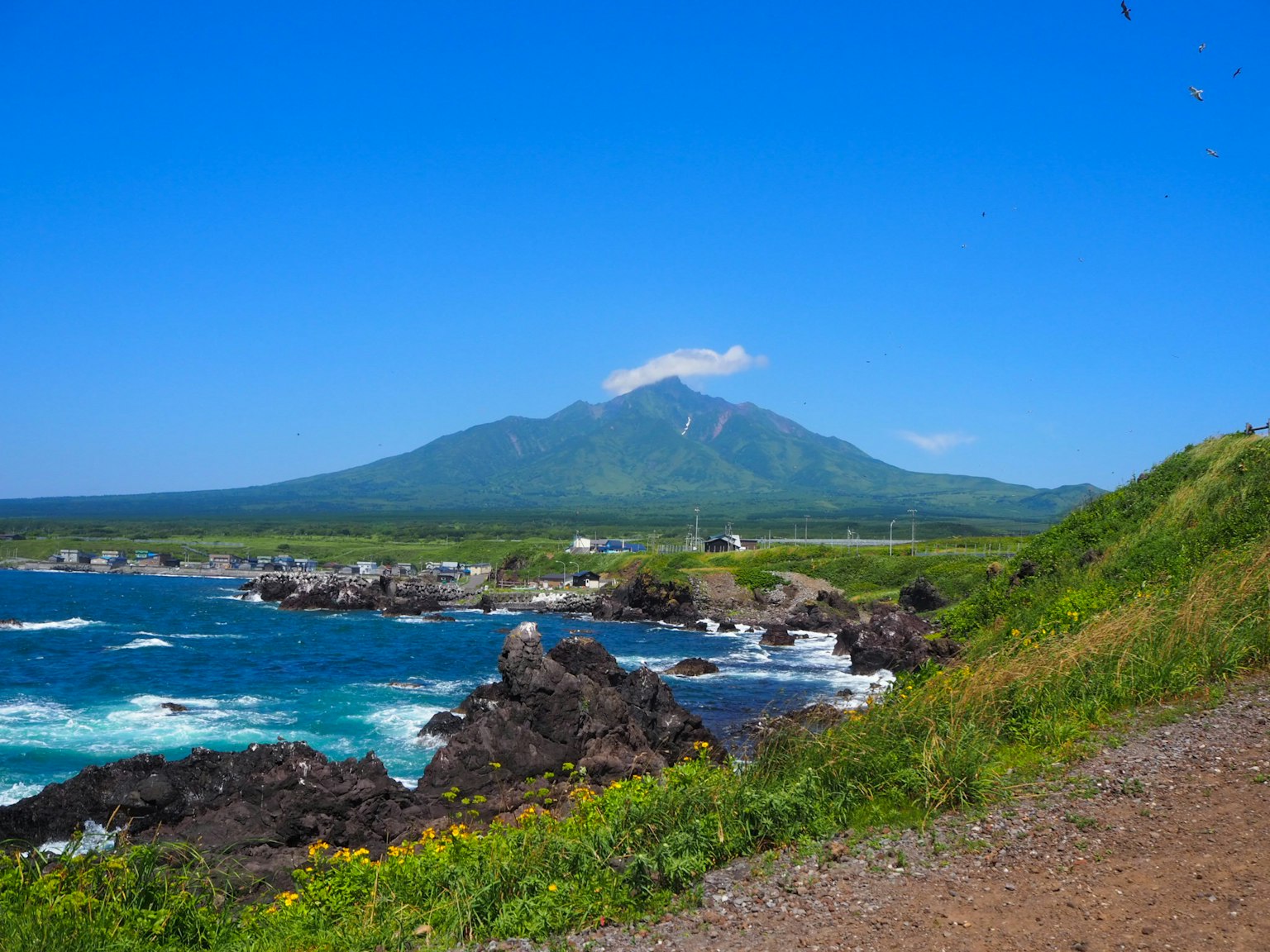 Pemandangan indah pegunungan besar dikelilingi langit biru dan lautan