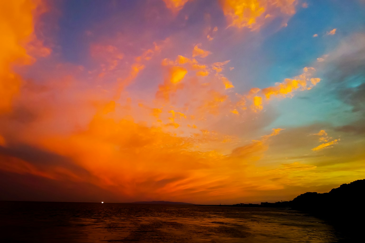 Langit matahari terbenam yang menakjubkan dengan nuansa oranye dan biru yang cerah di atas lautan