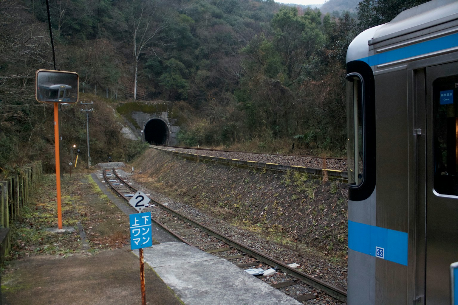A scenic view of a train station featuring a tunnel entrance and railway tracks