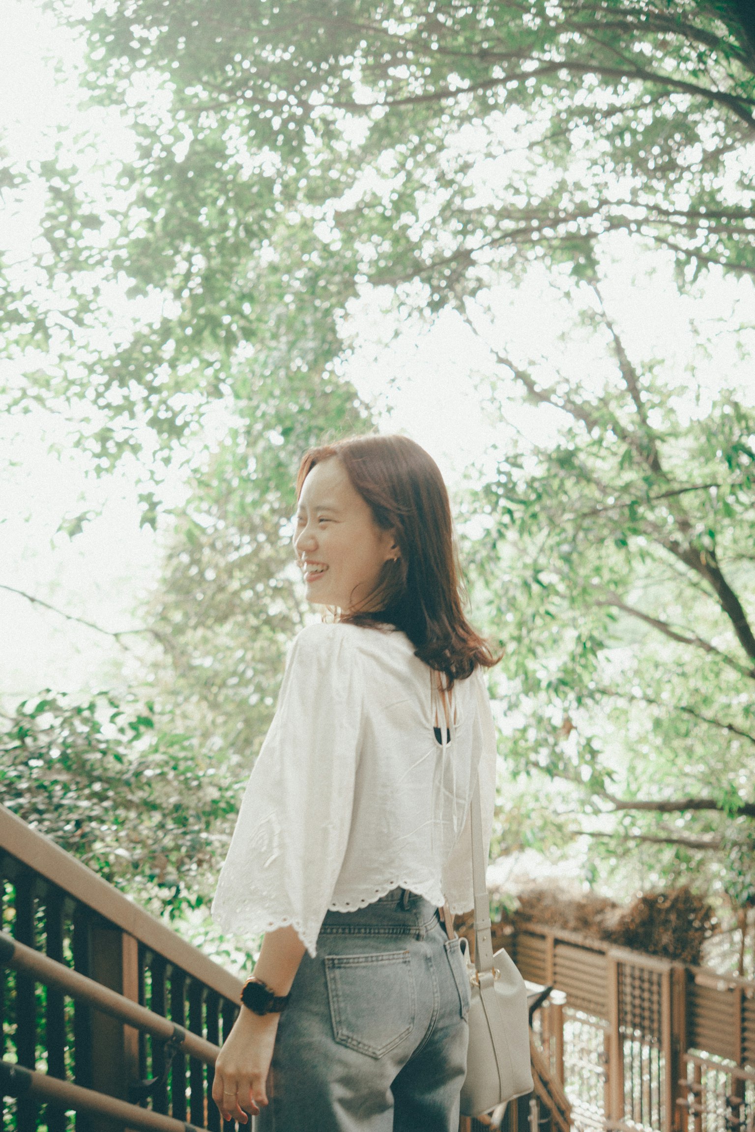 一位女性走在绿树环绕的木栈道上