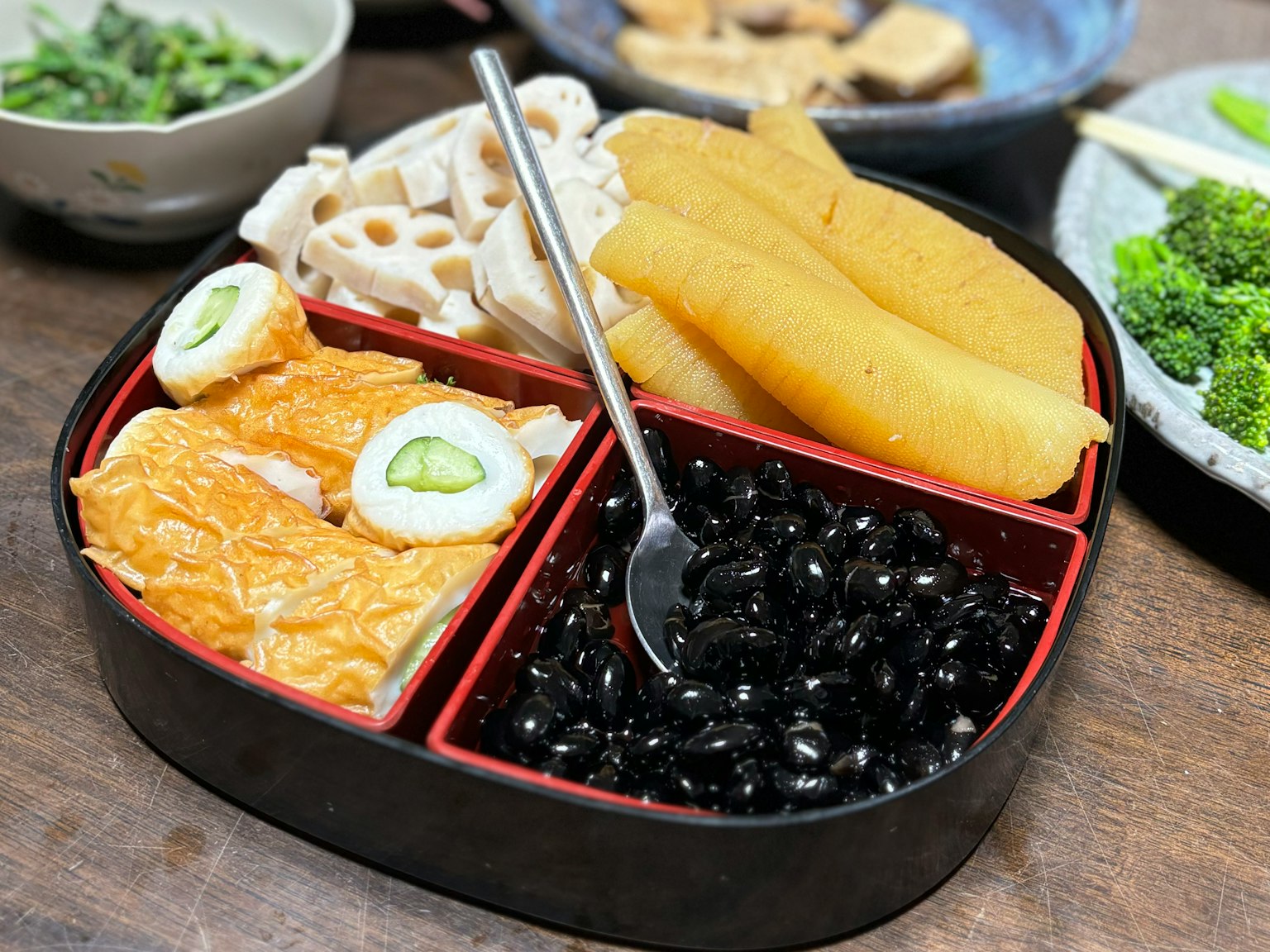 Eine schön arrangierte Bento-Box mit verschiedenen Zutaten, darunter Fisch, Gemüse und schwarzen Reis