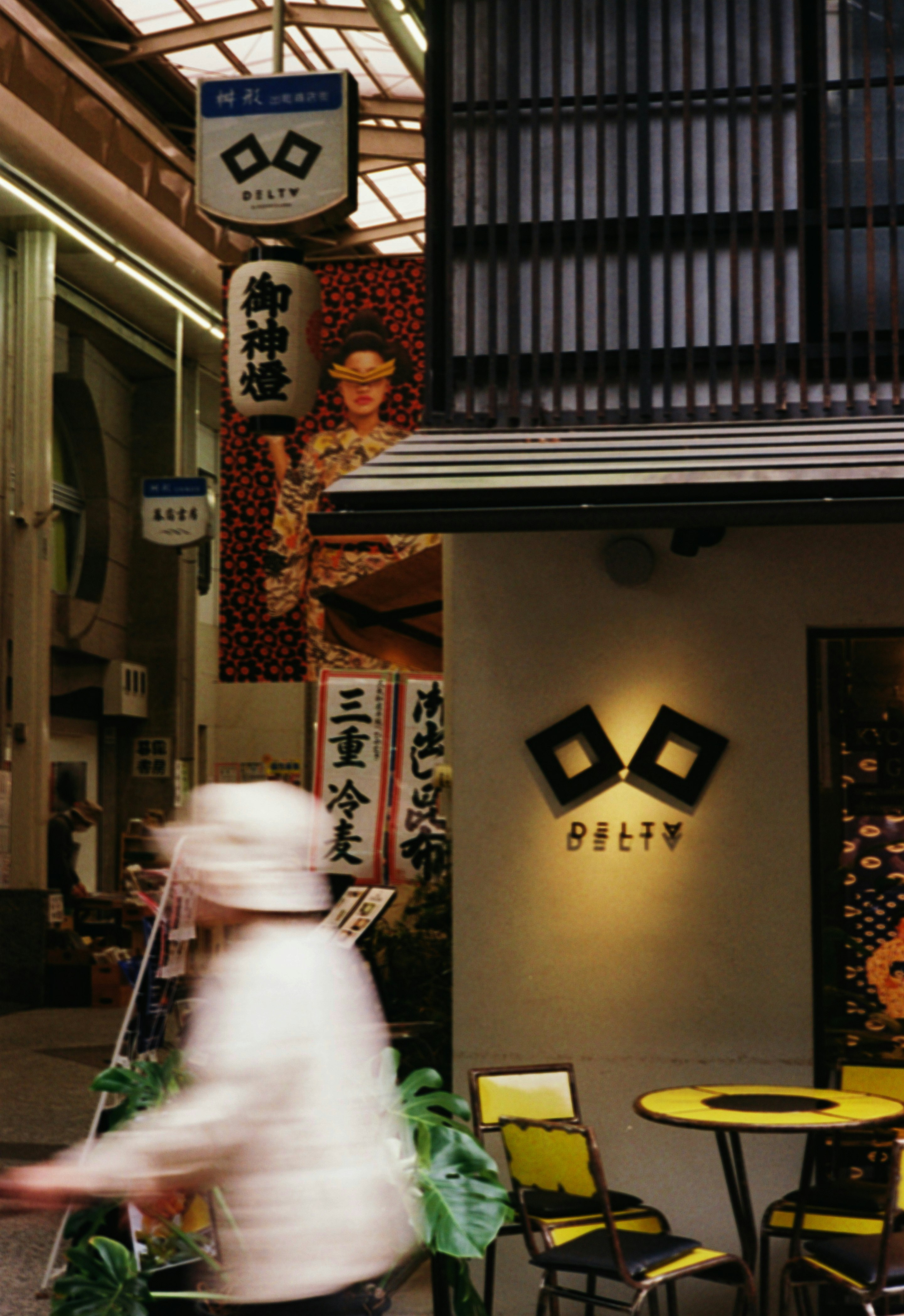A narrow alley in Demachimasugata Shopping Street with passing people and shop signs