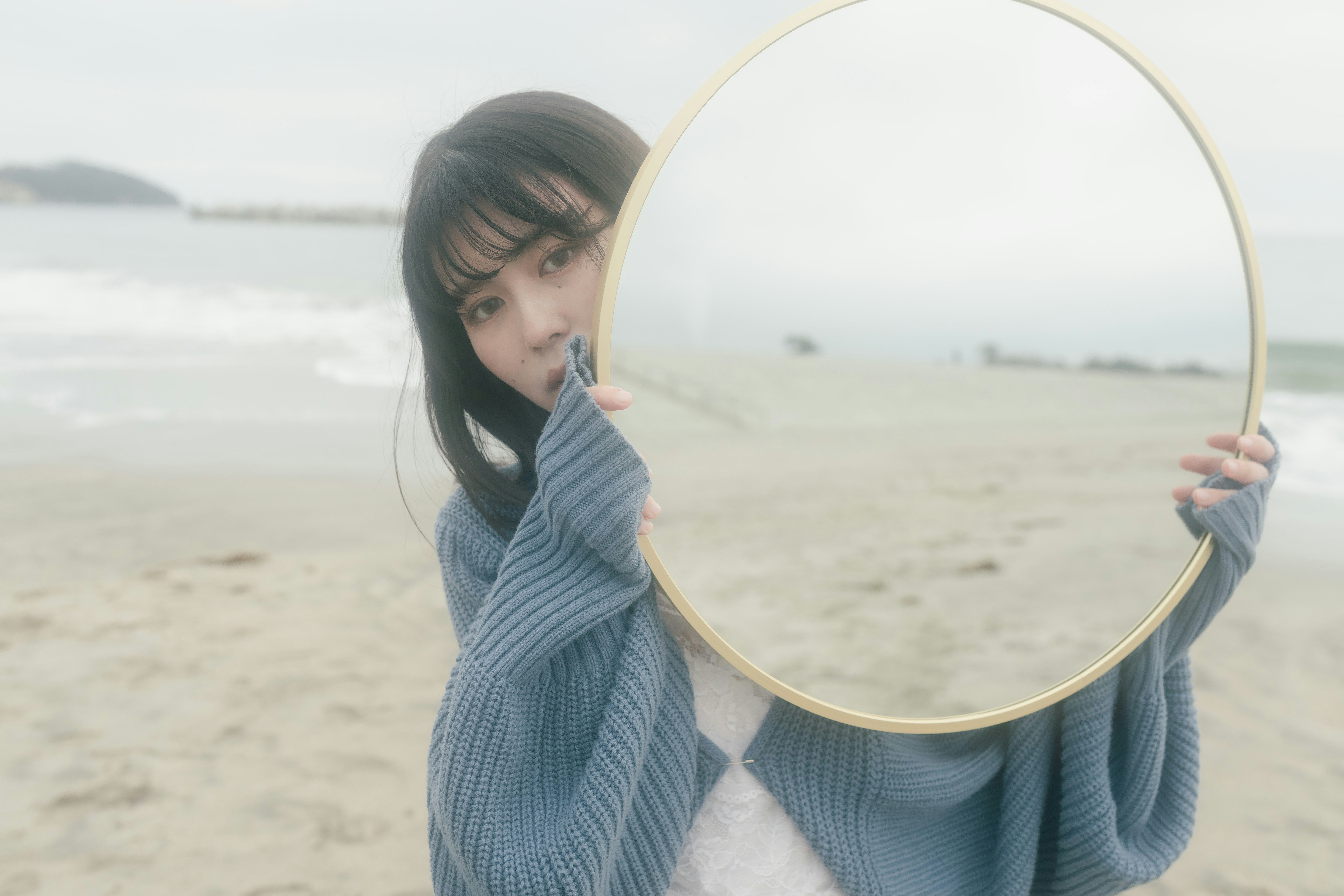 砂浜で丸い鏡を持つ女性