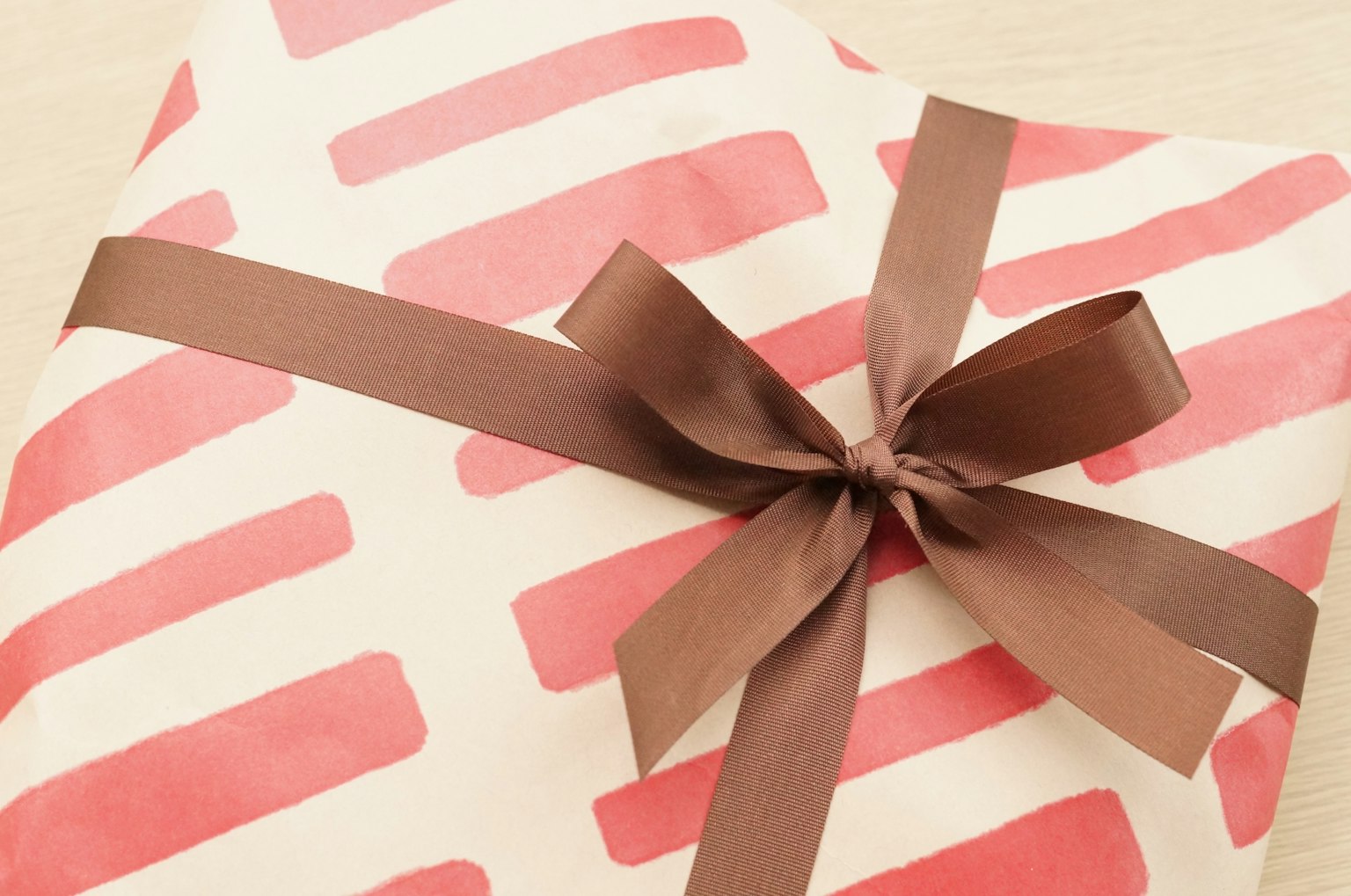 Ein Geschenk, das in rot gestreiftem Papier eingewickelt und mit einem braunen Band gebunden ist
